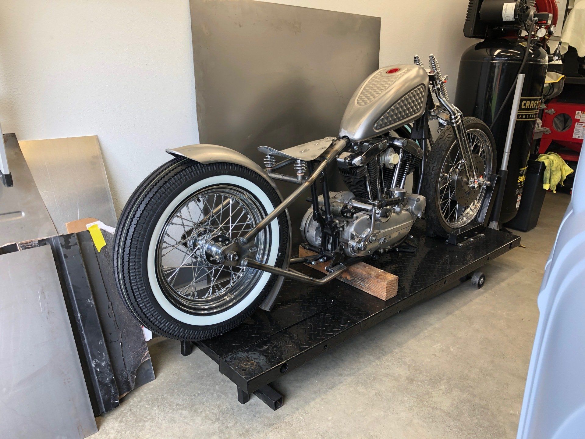 A motorcycle is sitting on a black cart in a garage.