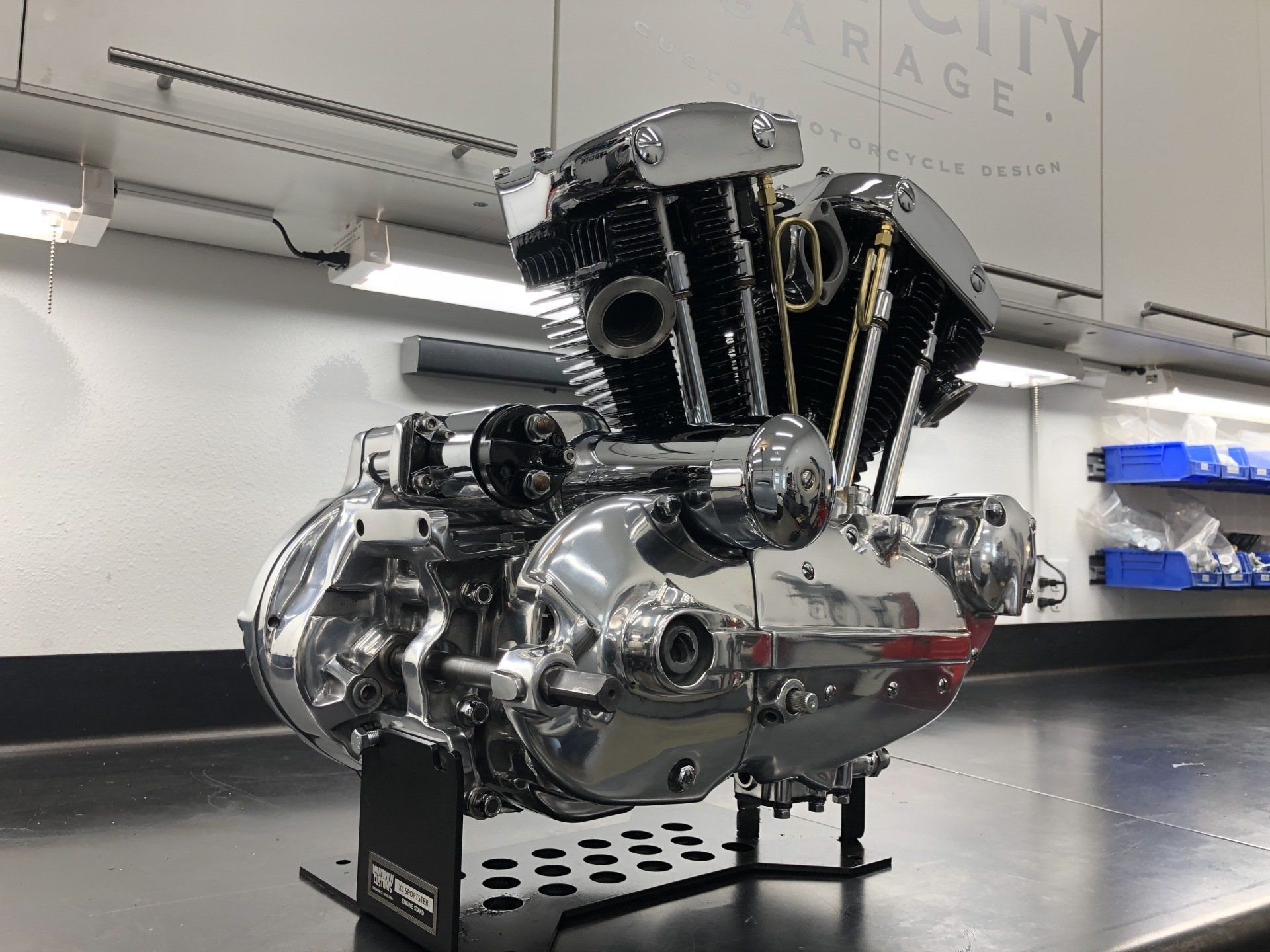 A motorcycle engine is sitting on a table in a garage.