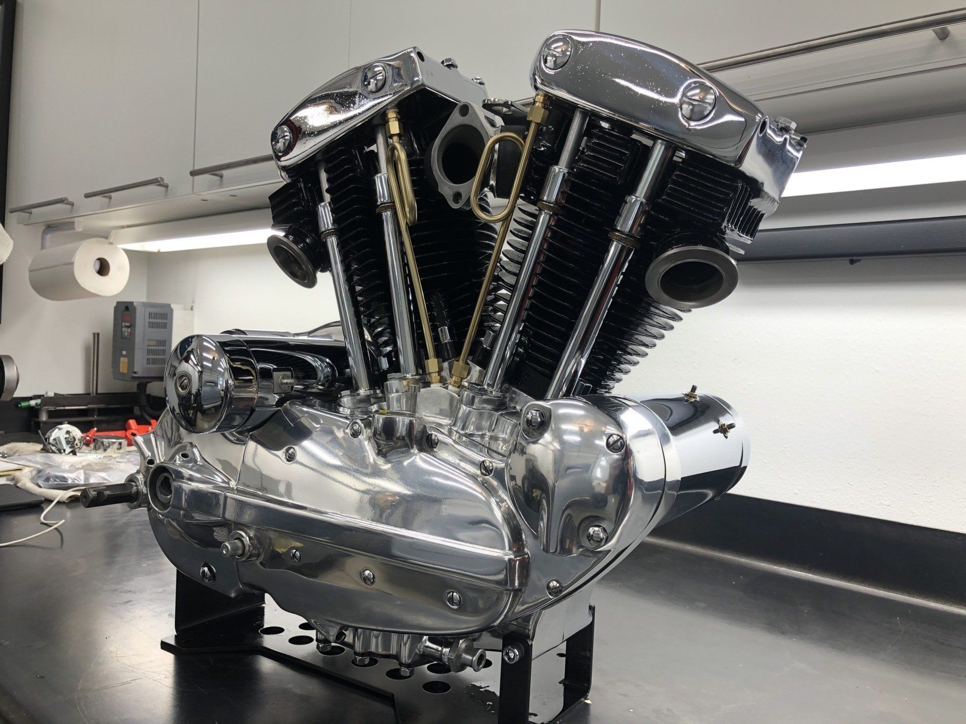 A motorcycle engine is sitting on a table in a garage.