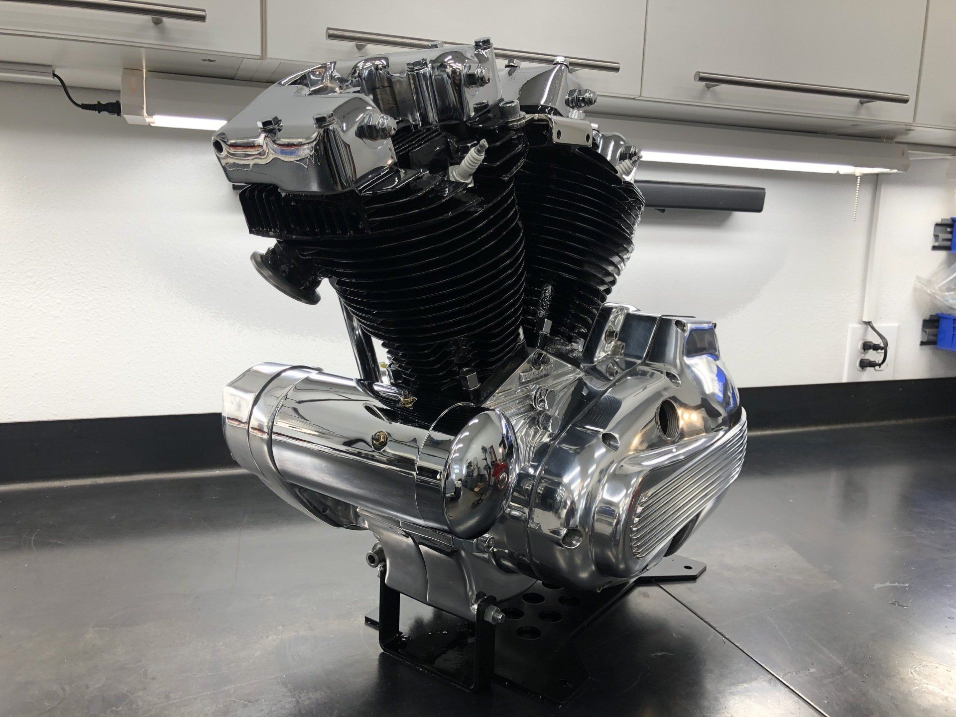 A motorcycle engine is sitting on a table in a garage.