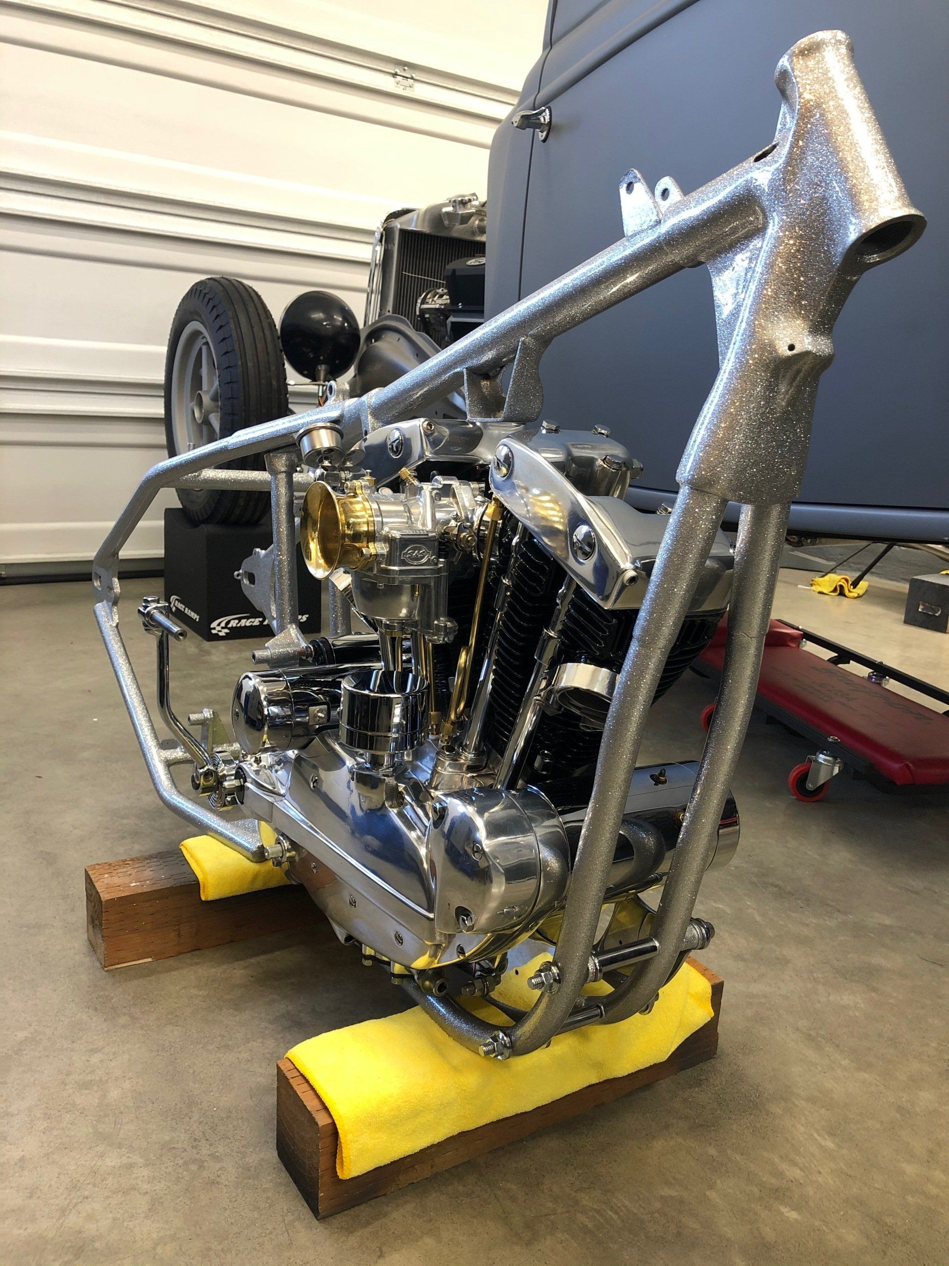 A motorcycle engine is sitting on a wooden stand in a garage.