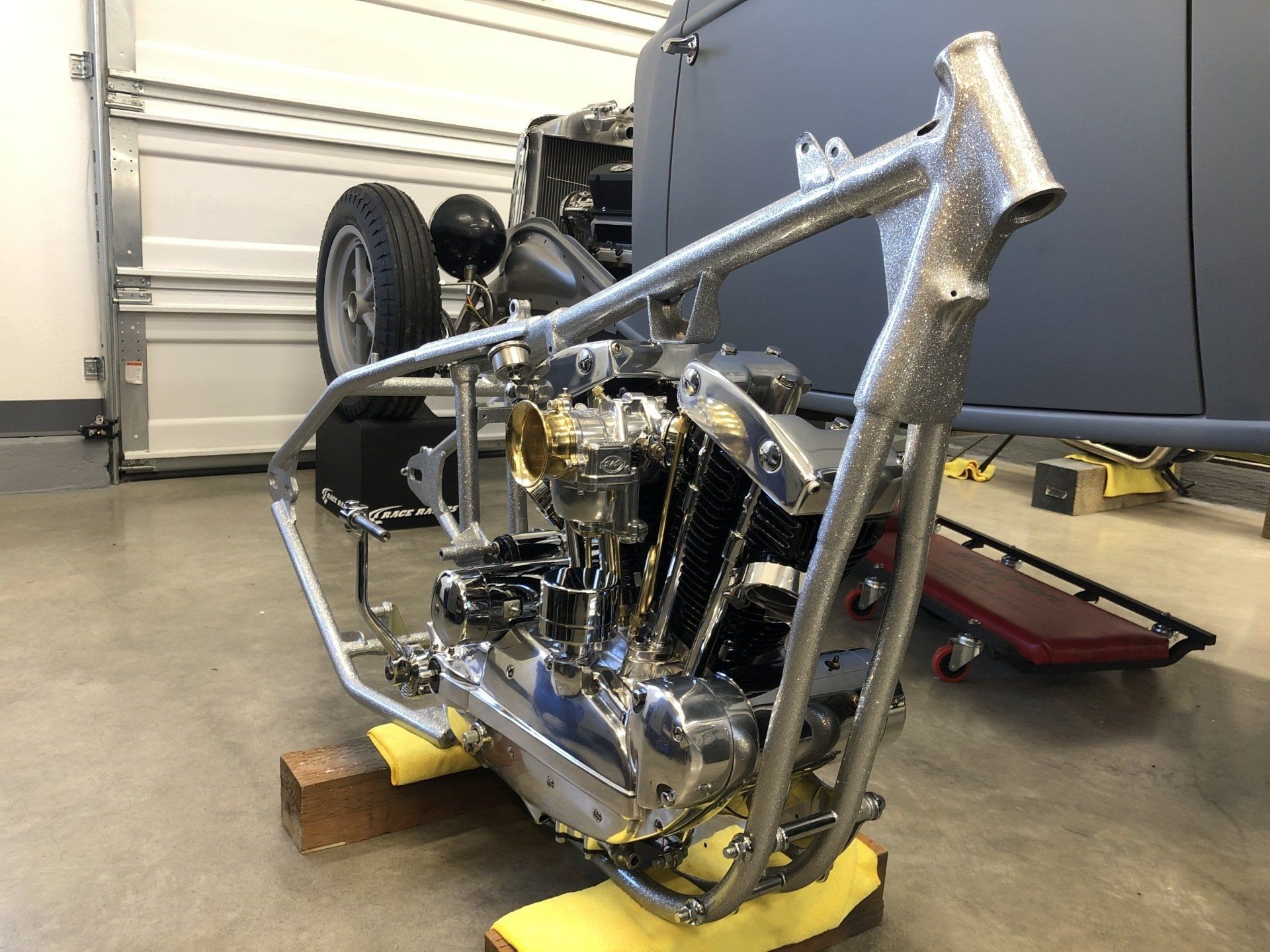 A motorcycle frame is sitting on a yellow cushion in a garage.
