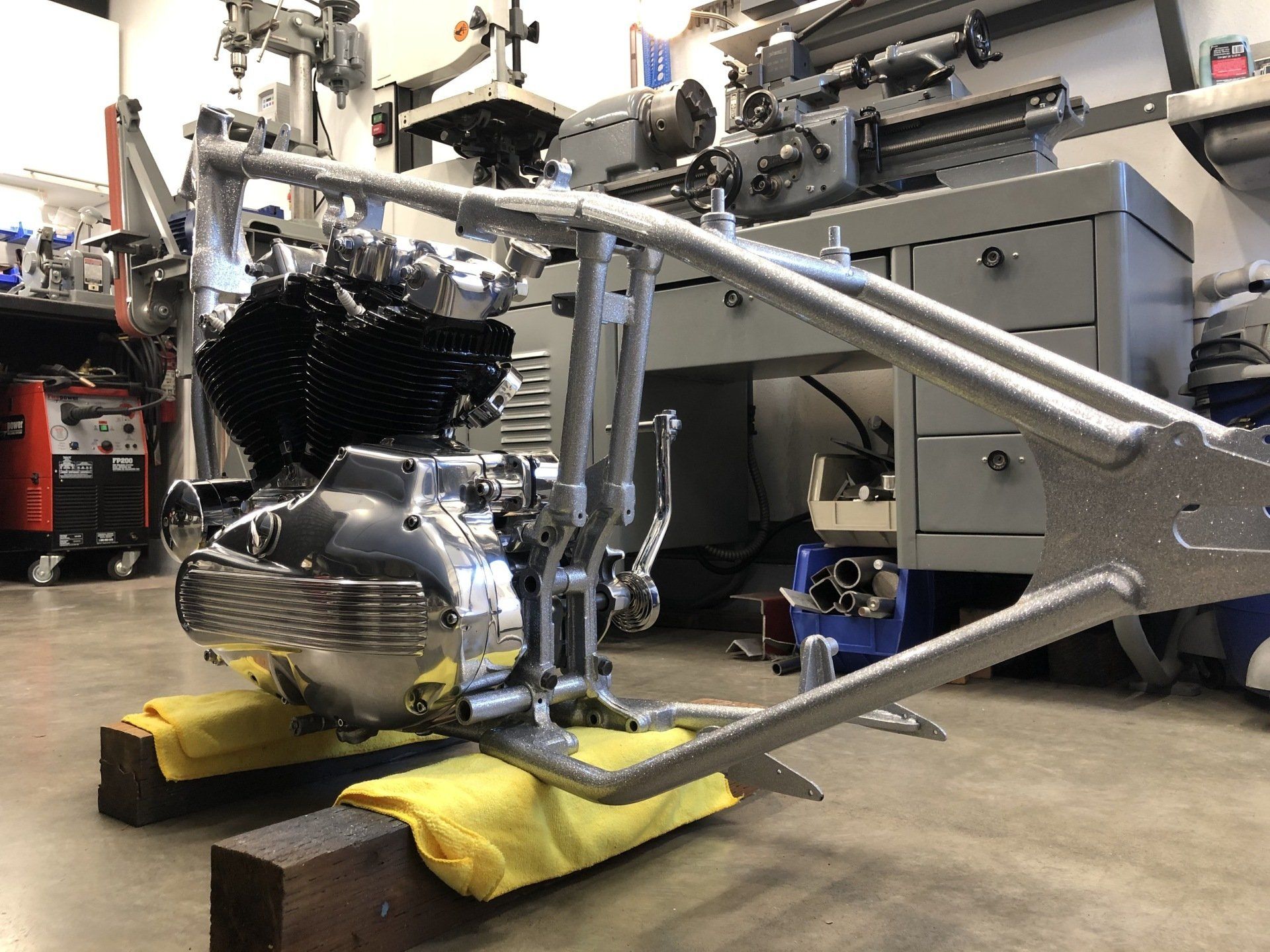 A motorcycle engine is sitting on a wooden block in a garage.