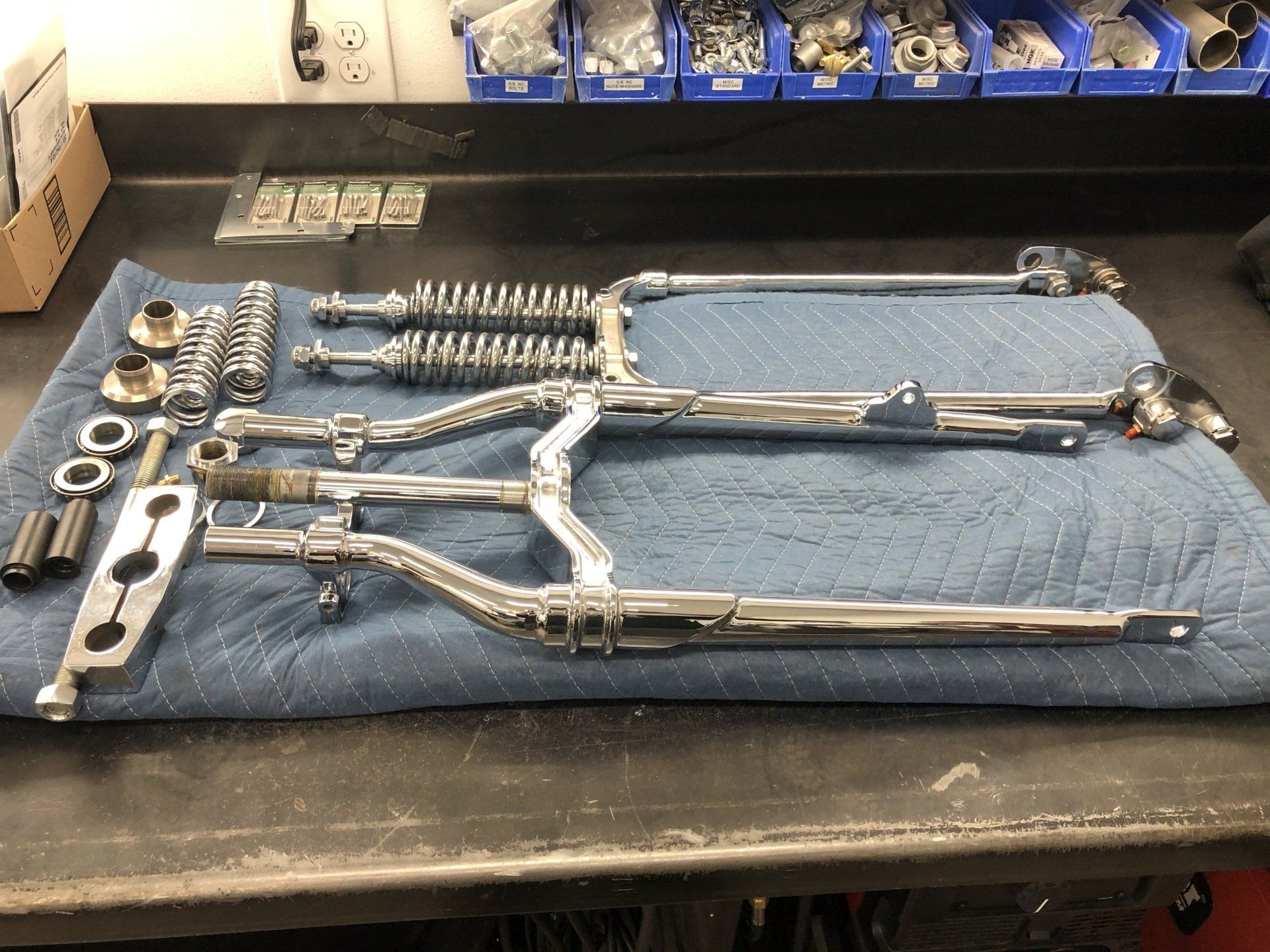 A motorcycle fork is laying on a blue towel on a table.