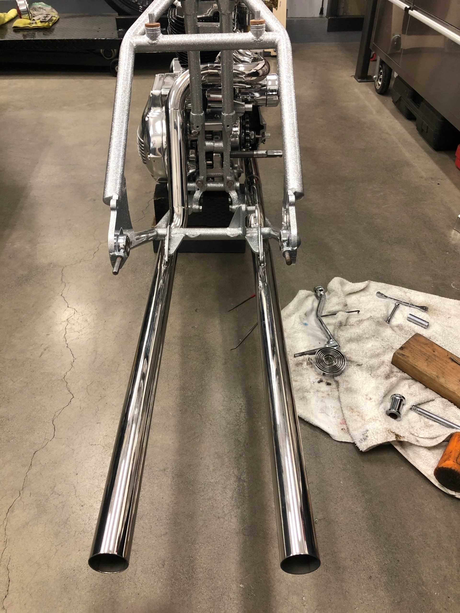 A motorcycle frame is sitting on the floor in a garage.