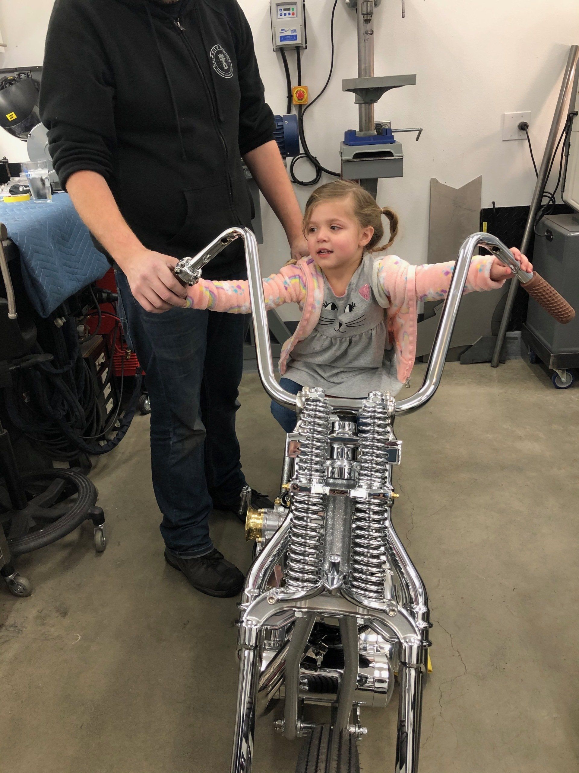 A little girl is sitting on a motorcycle in a garage
