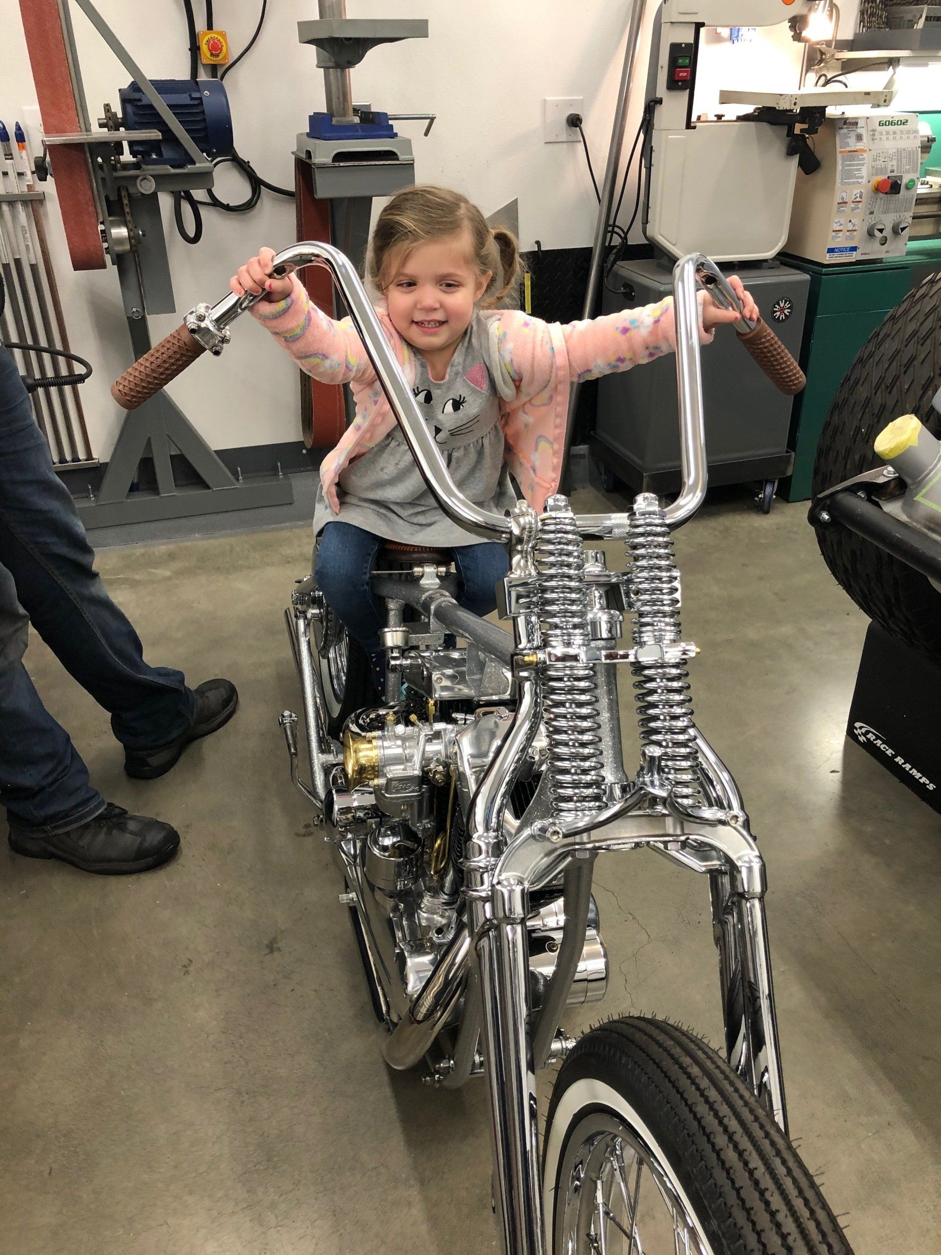 A little girl is sitting on a motorcycle in a garage.