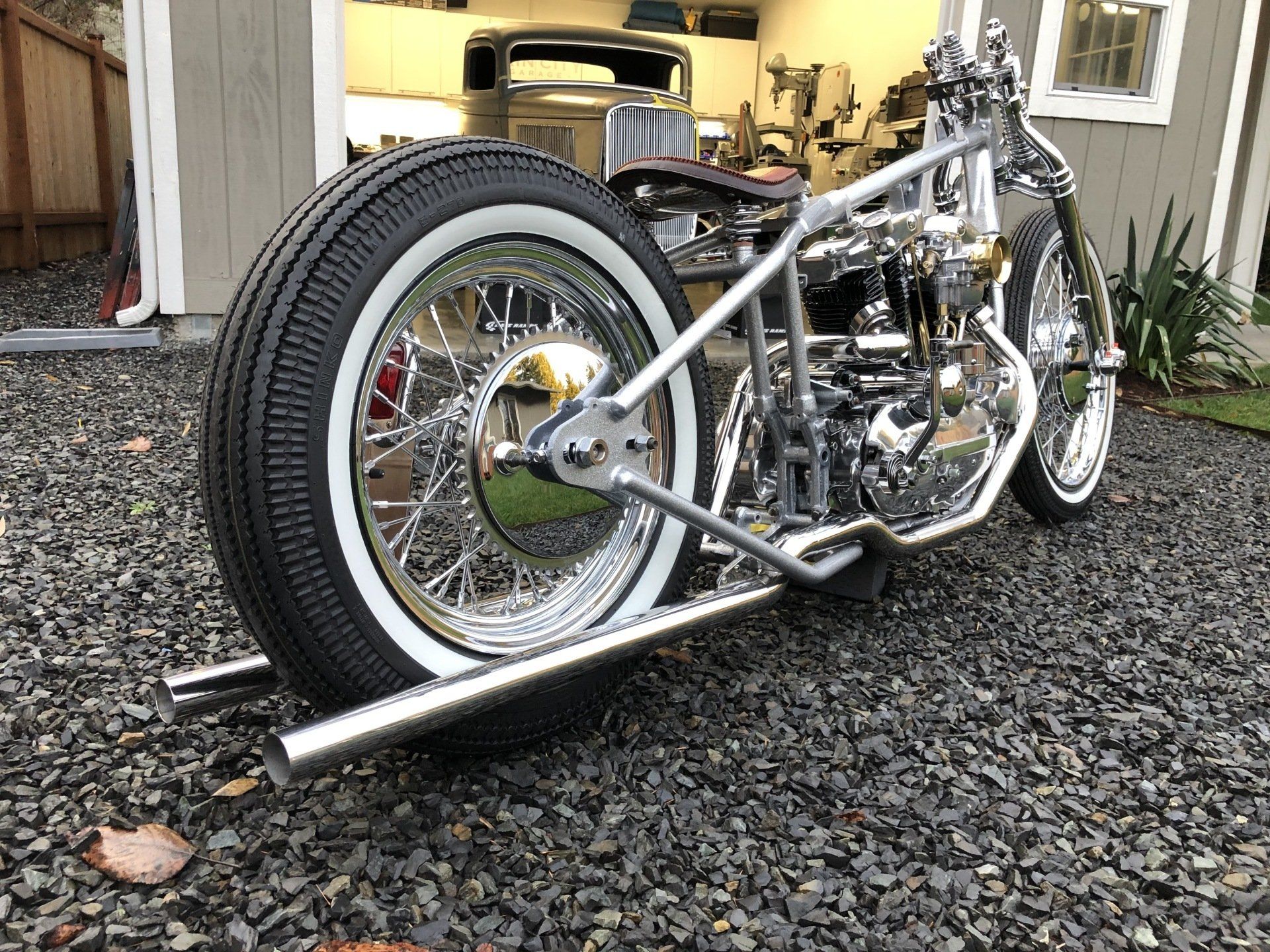 A motorcycle is parked on gravel in front of a garage.