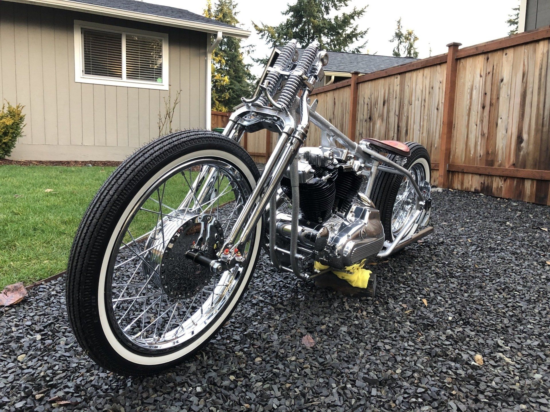 A motorcycle is parked on gravel in front of a house.