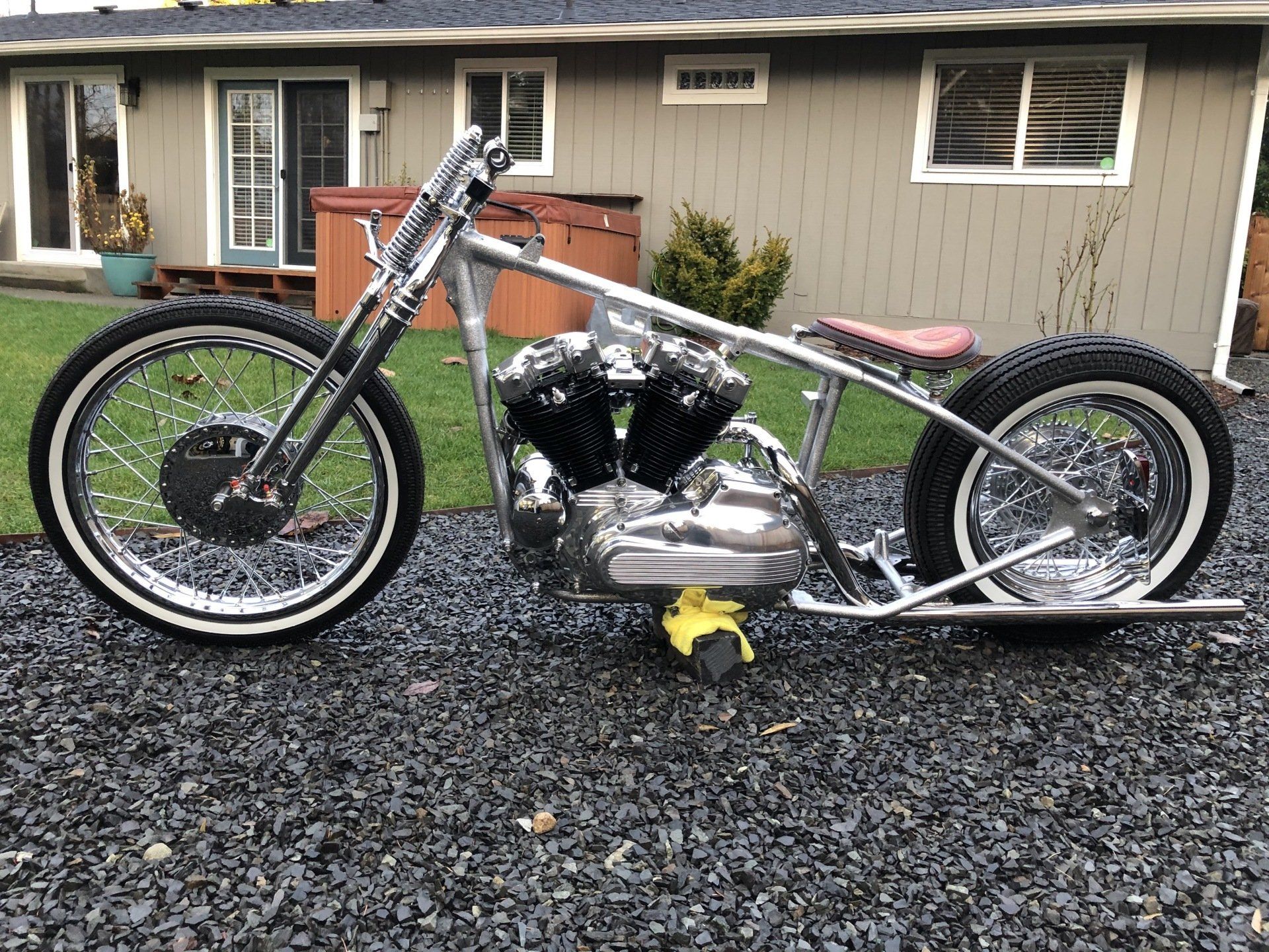 A motorcycle is parked on gravel in front of a house.