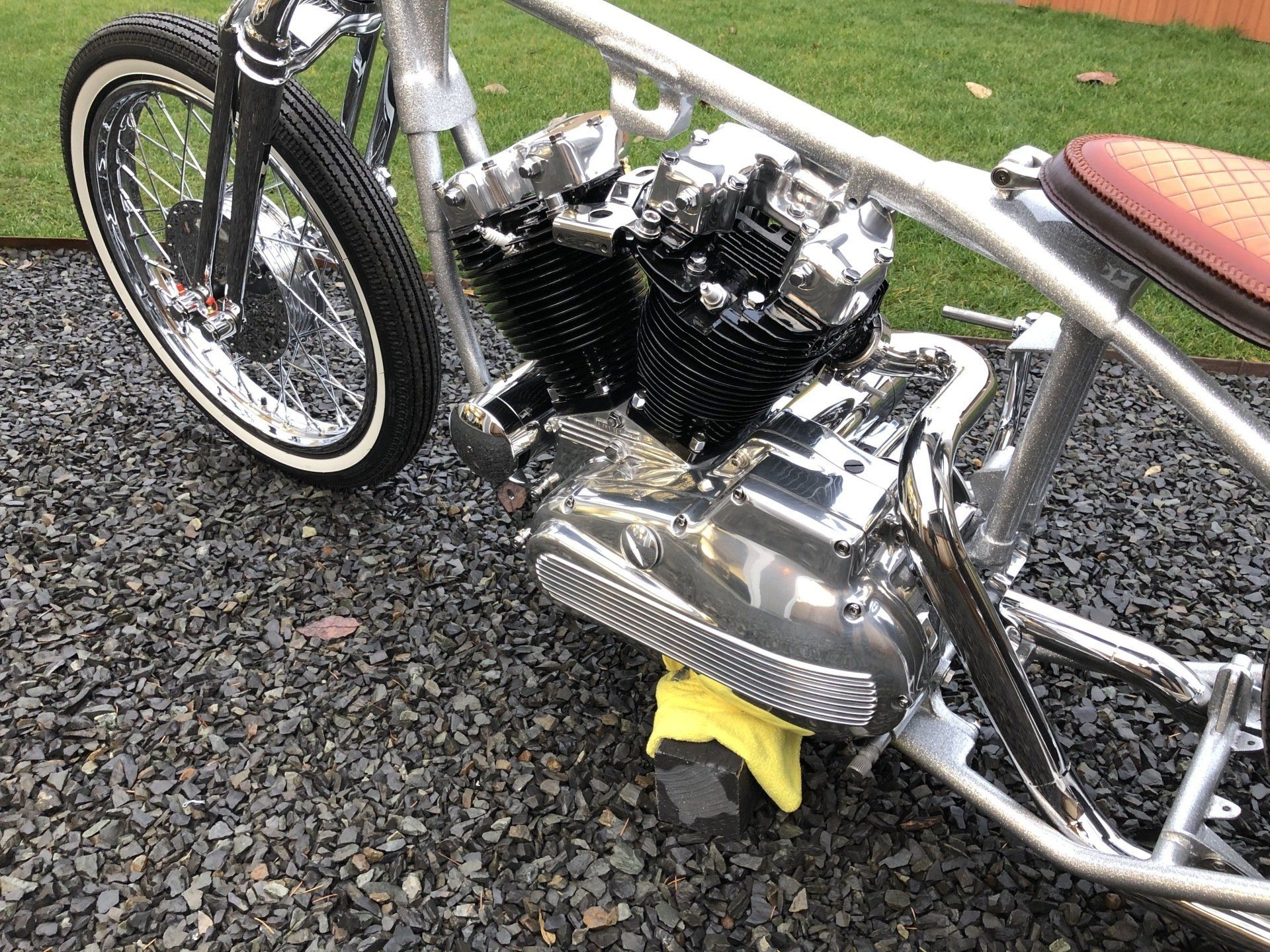 A close up of a motorcycle engine on a gravel road.