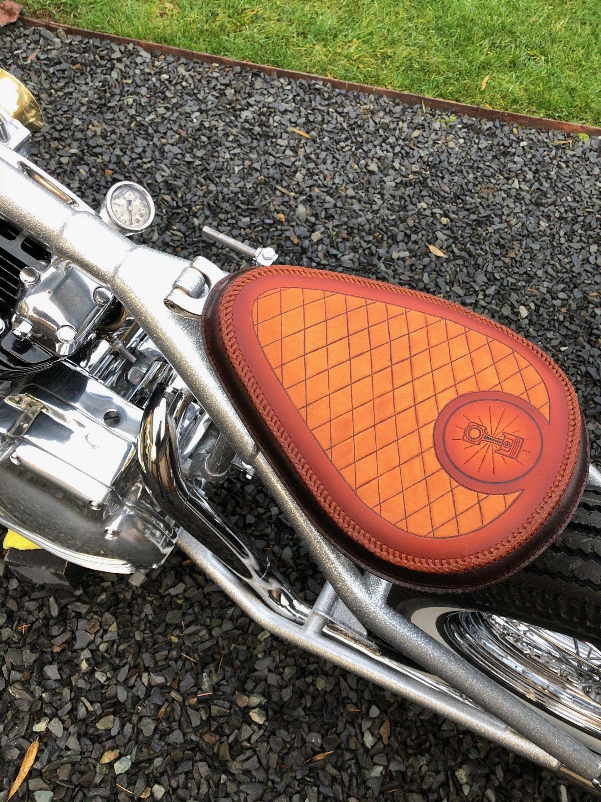 A motorcycle with a red seat is parked on gravel.