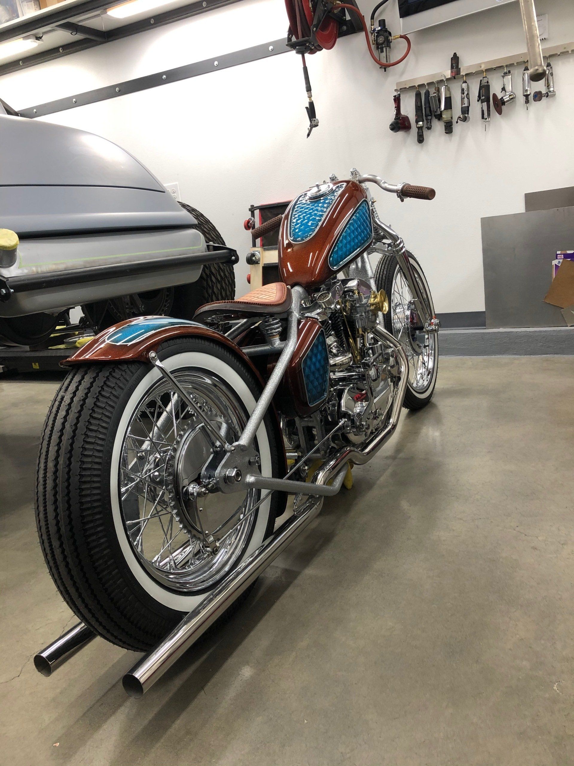 A motorcycle is parked in a garage next to a car.