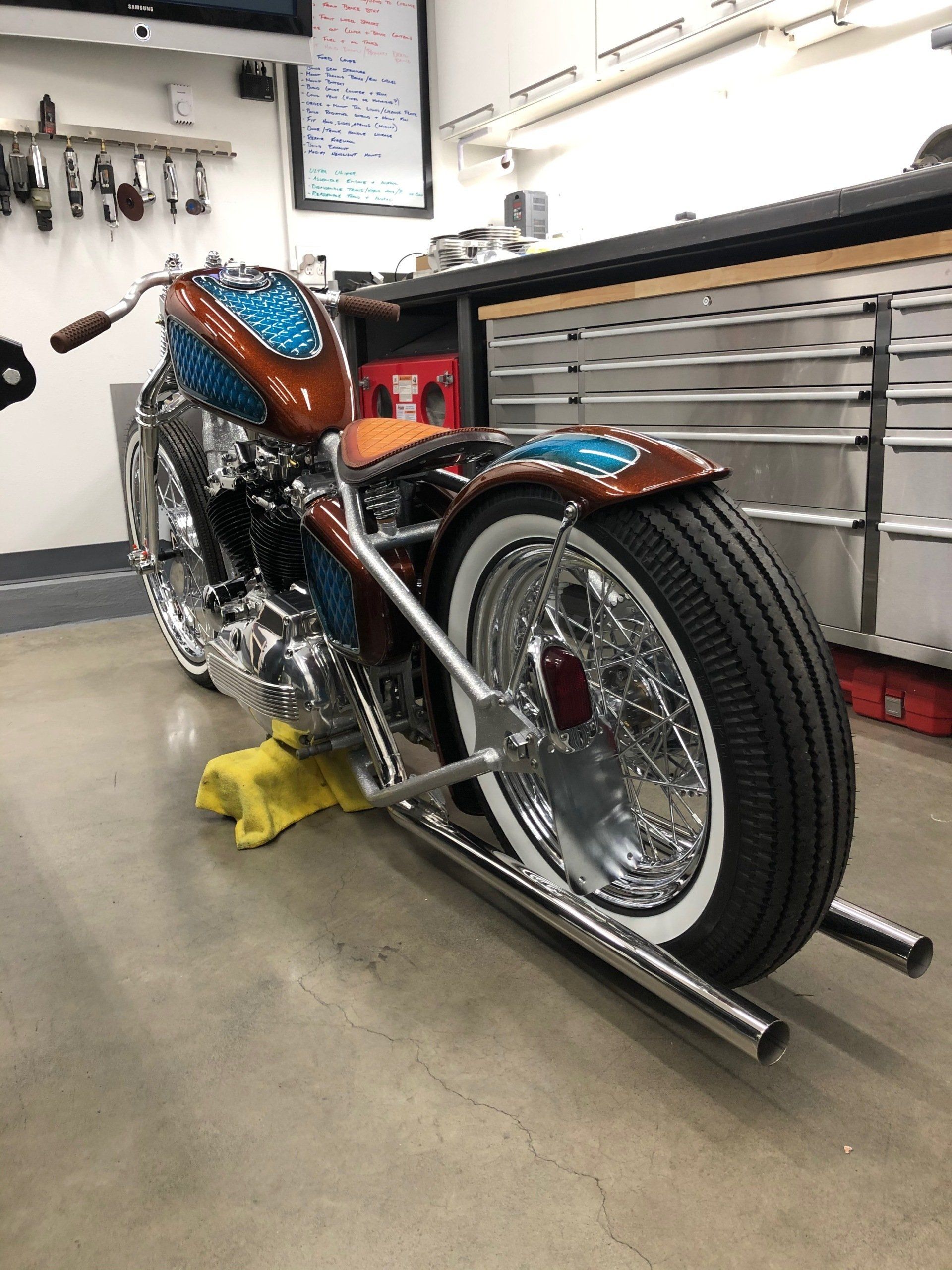 A motorcycle is parked in a garage with white tires.