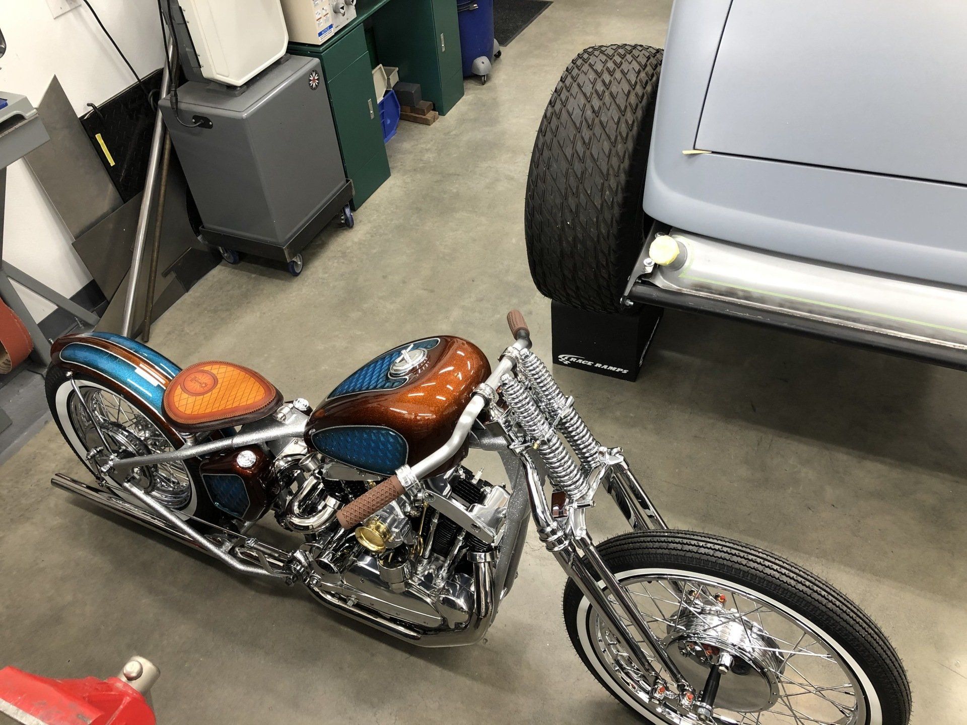 A motorcycle is parked in a garage next to a car