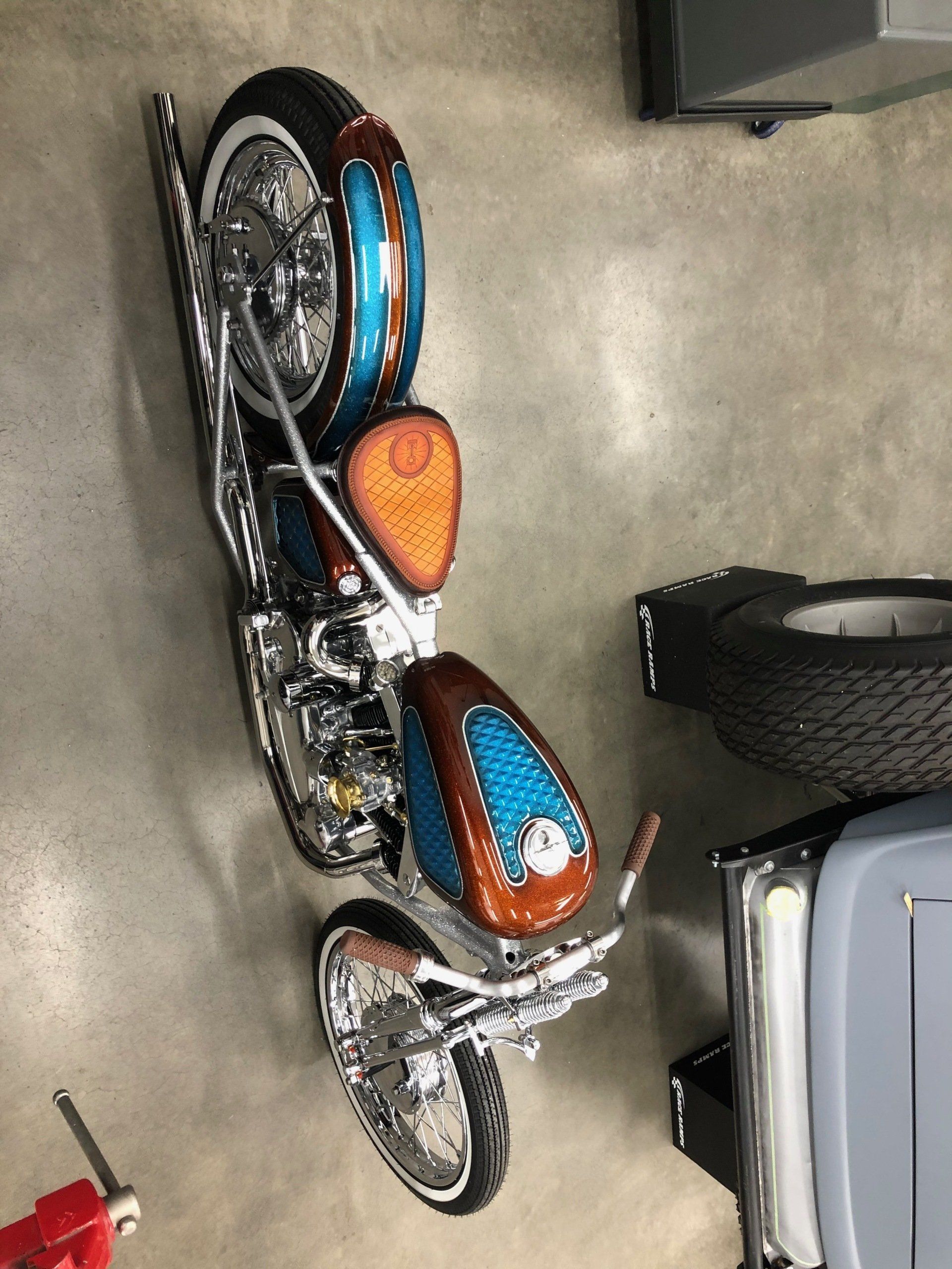 A motorcycle is parked in a garage next to a tire.