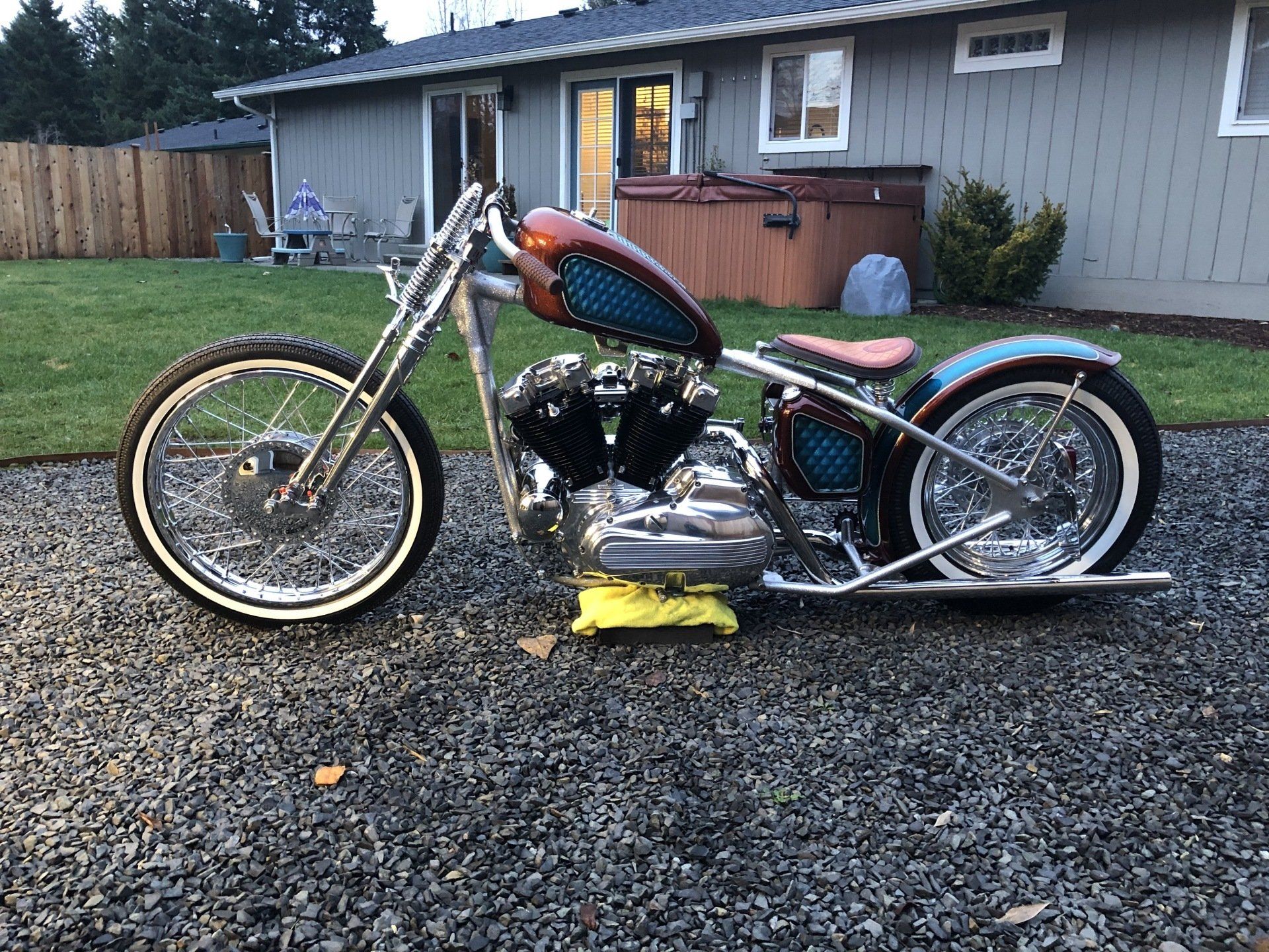 A chopper motorcycle is parked in front of a house.