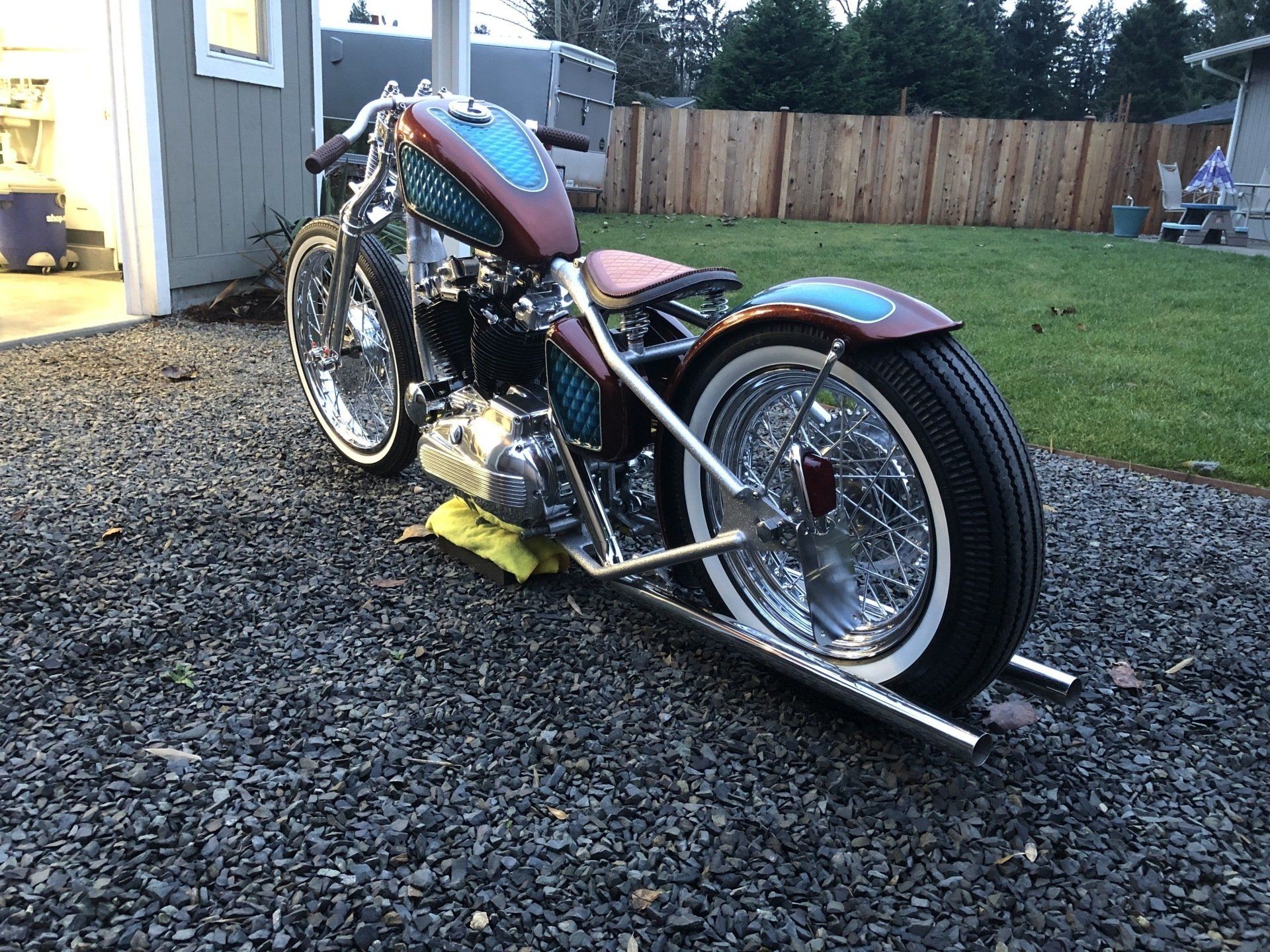 A motorcycle is parked on gravel in front of a garage