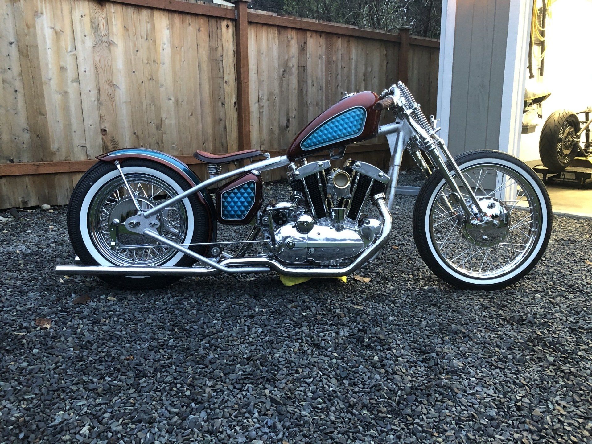 A motorcycle is parked on gravel in front of a garage.