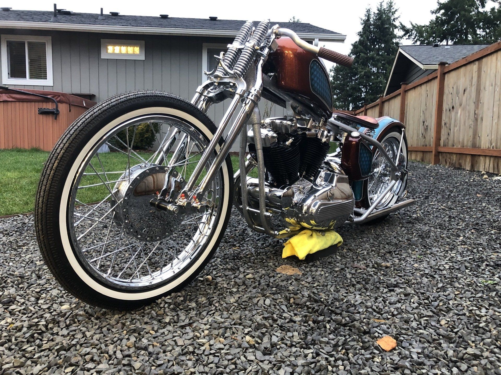A motorcycle is parked in a gravel driveway in front of a house.