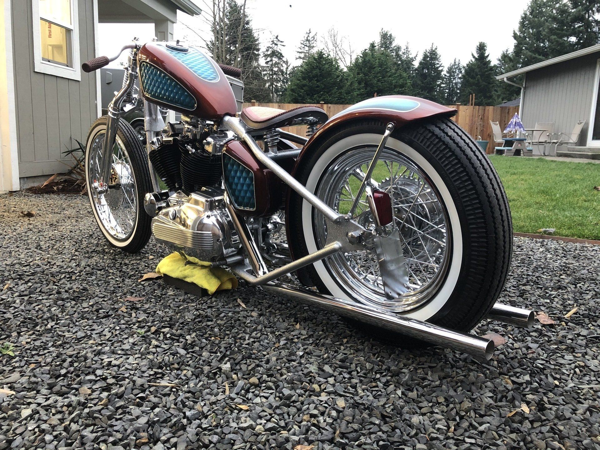 A motorcycle is parked on gravel in front of a house.