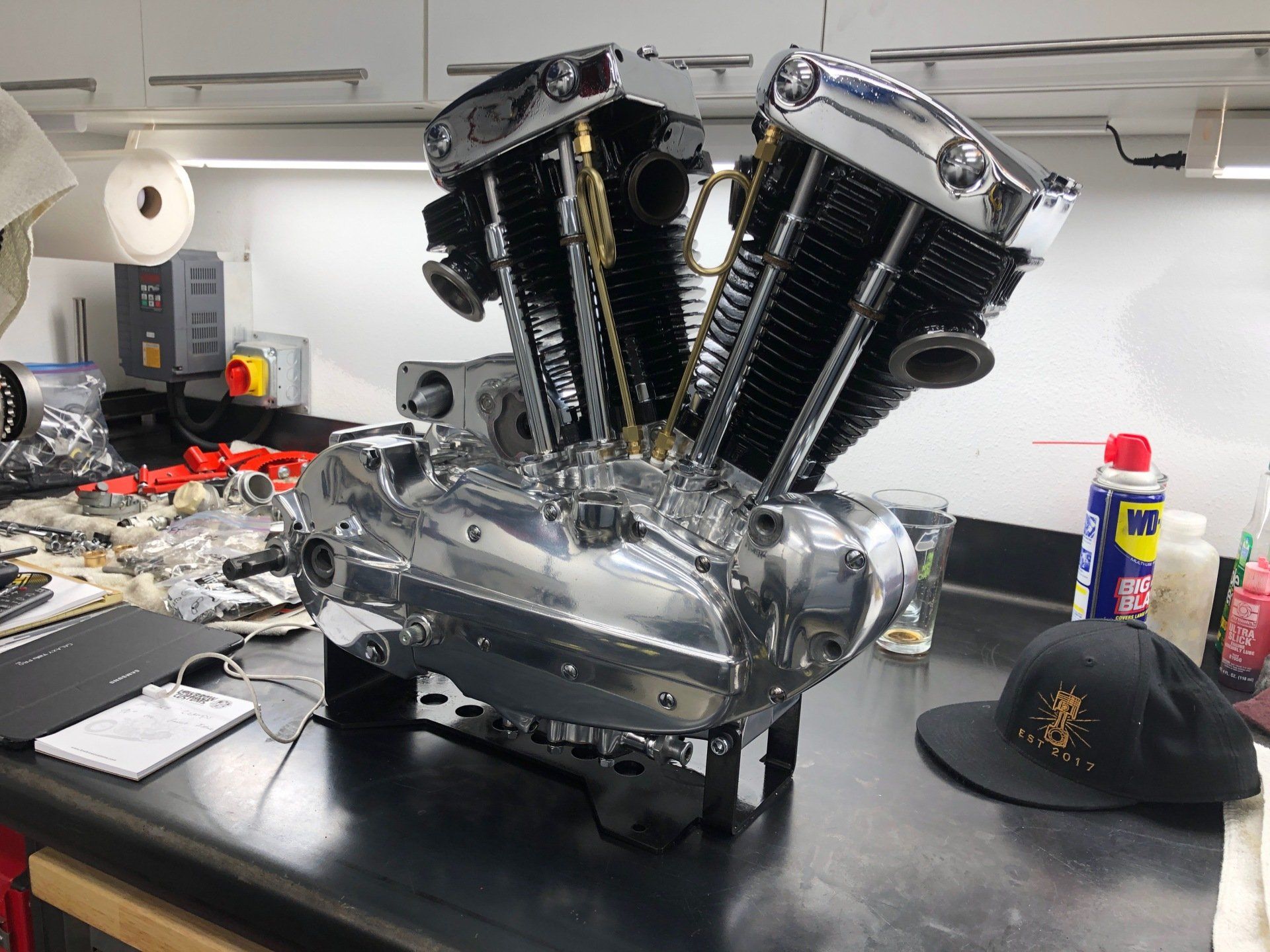 A motorcycle engine is sitting on a table in a garage.