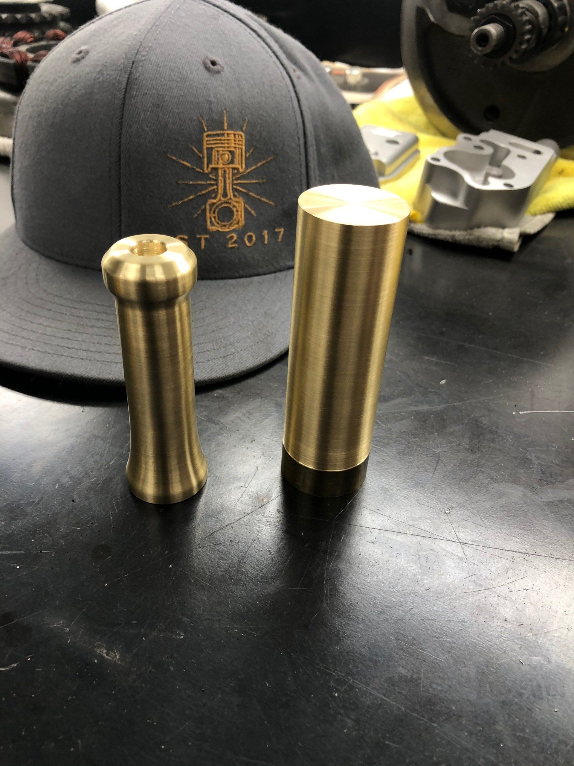 Two brass cylinders are sitting on a table next to a hat