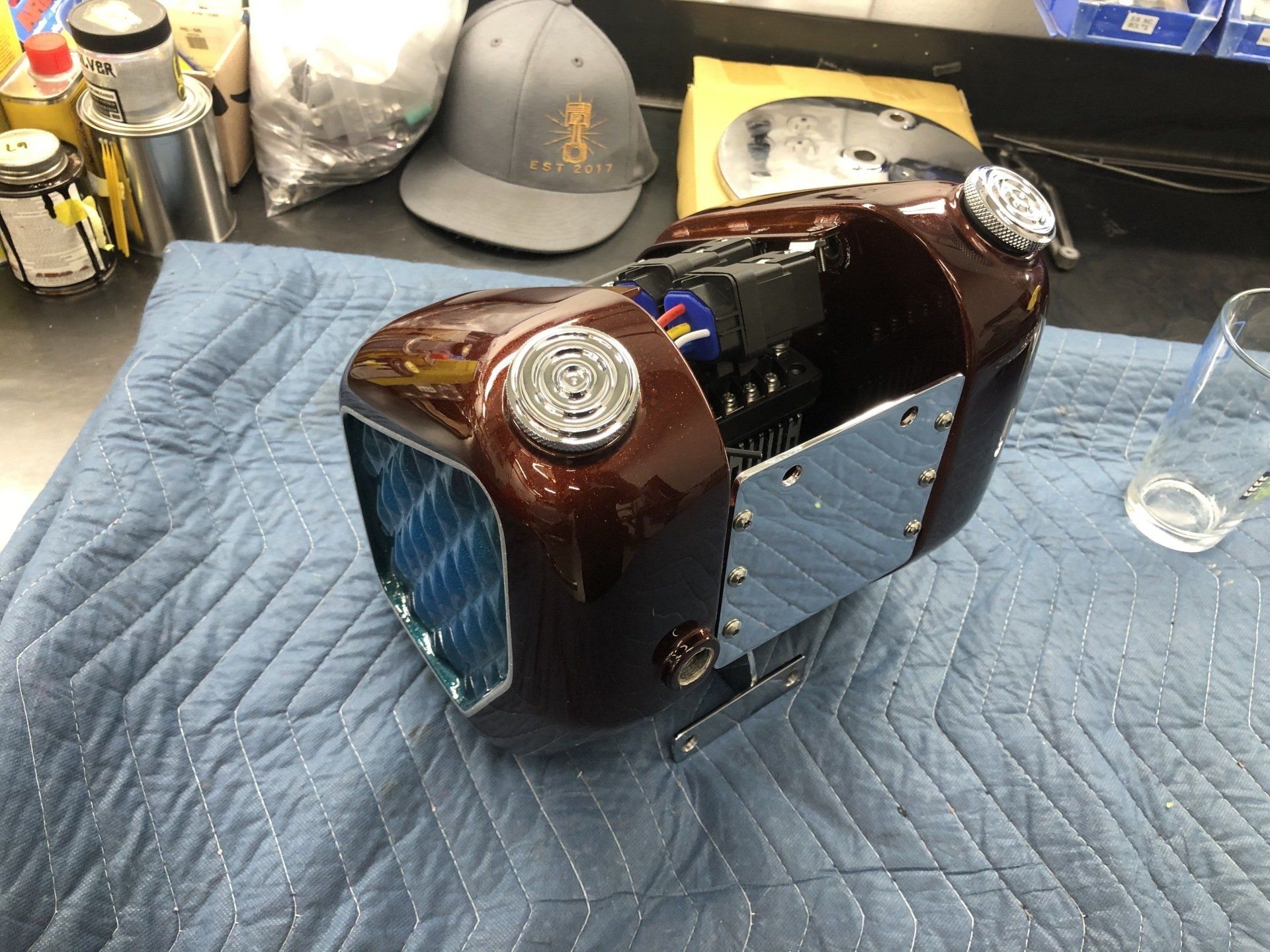 A motorcycle tank is sitting on a blue blanket on a table.