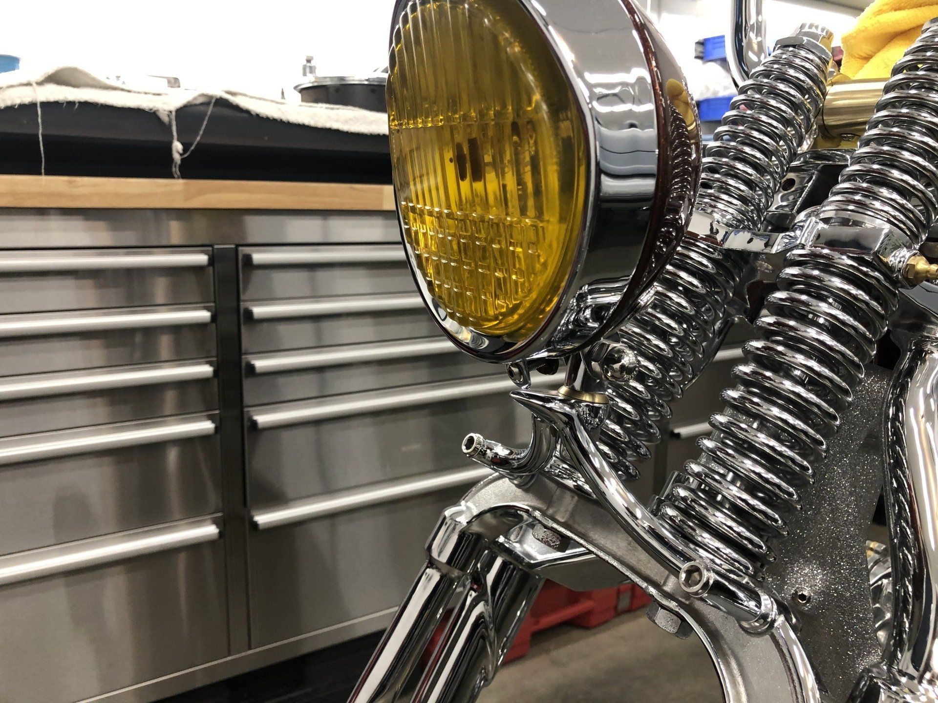 A close up of a motorcycle with a yellow headlight in a garage.