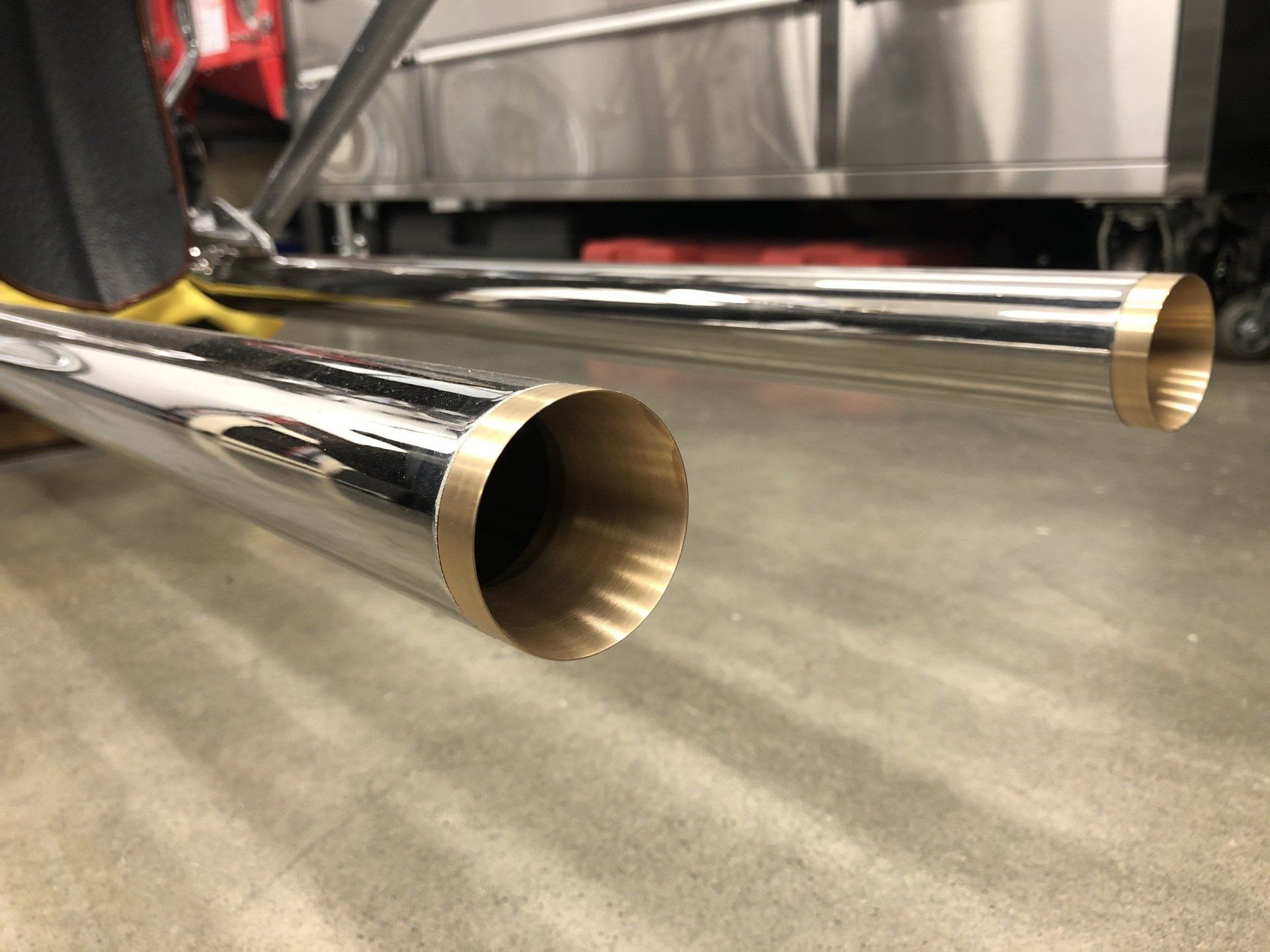 A pair of exhaust pipes are sitting on a concrete floor.