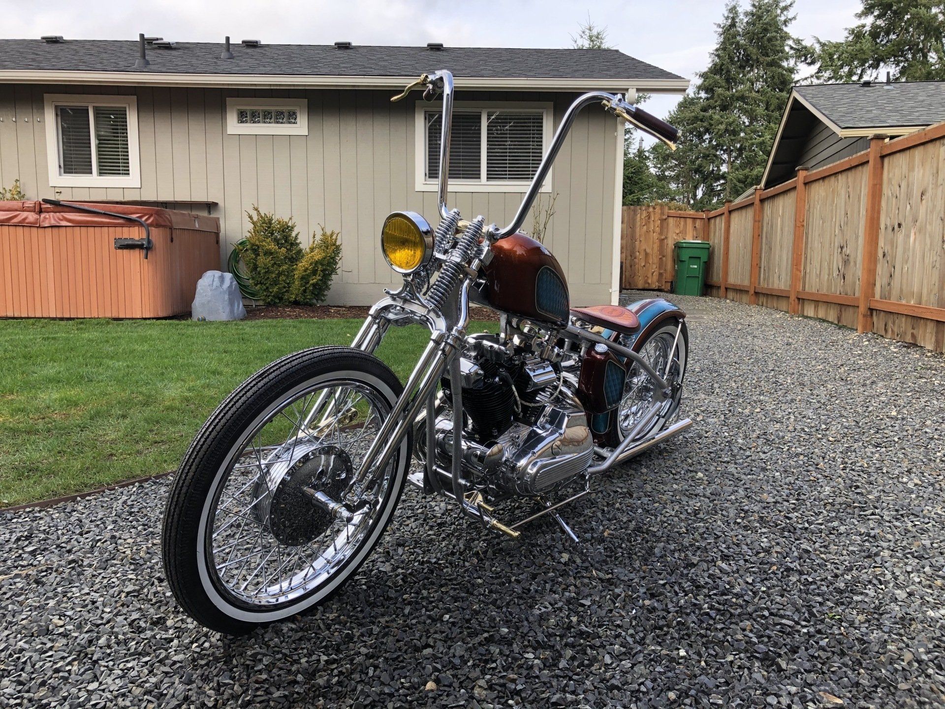 A chopper motorcycle is parked in front of a house.