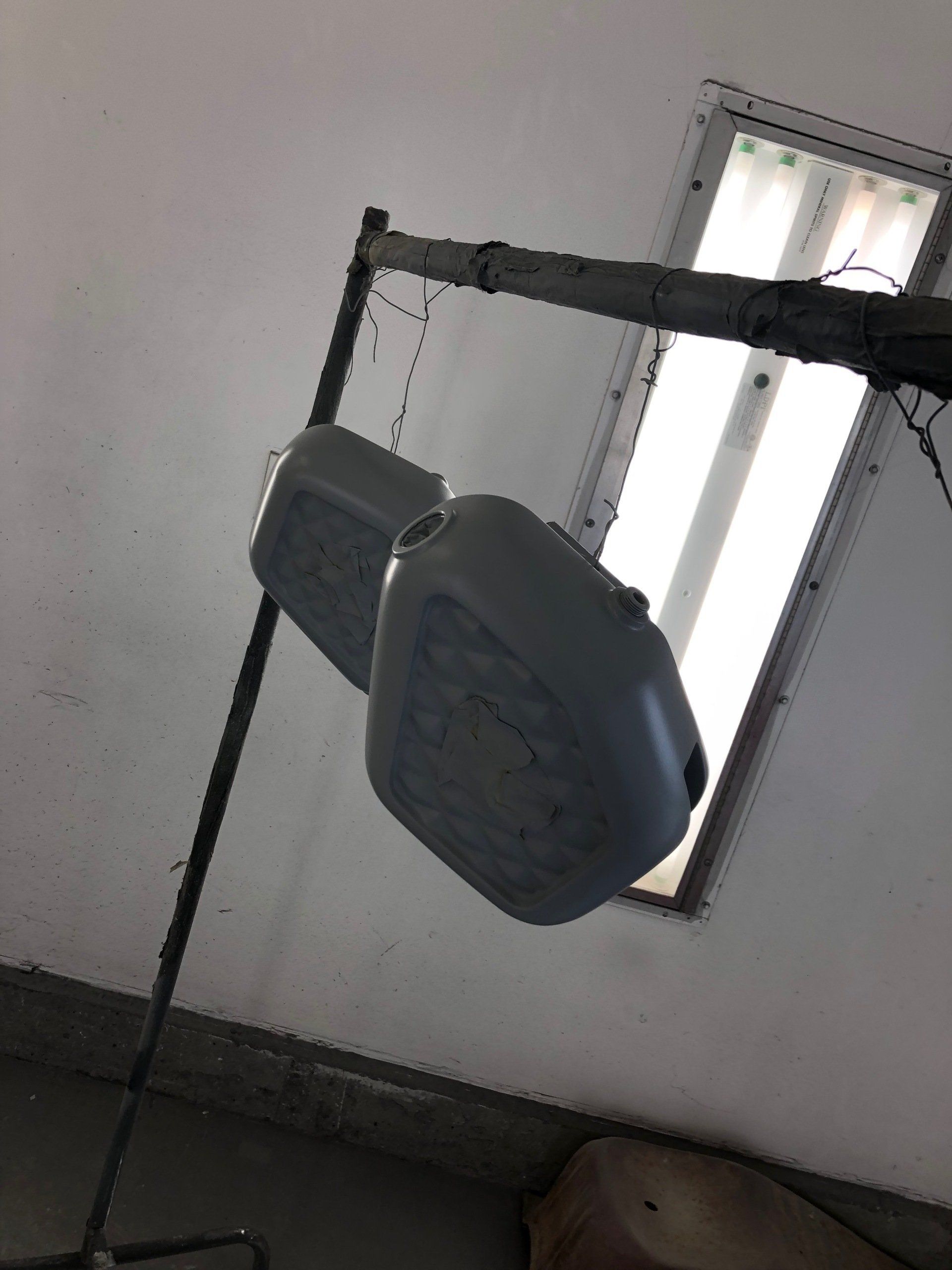 Two gray containers are hanging on a rack in a room