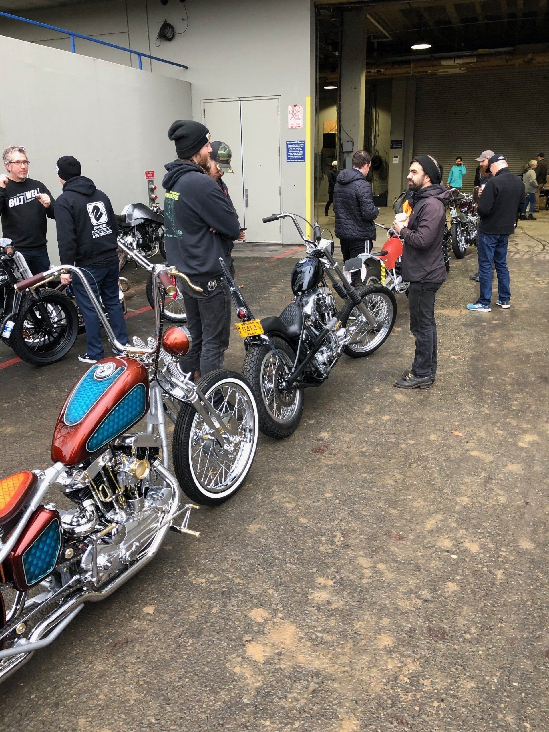 A group of men are standing around motorcycles in a parking lot.