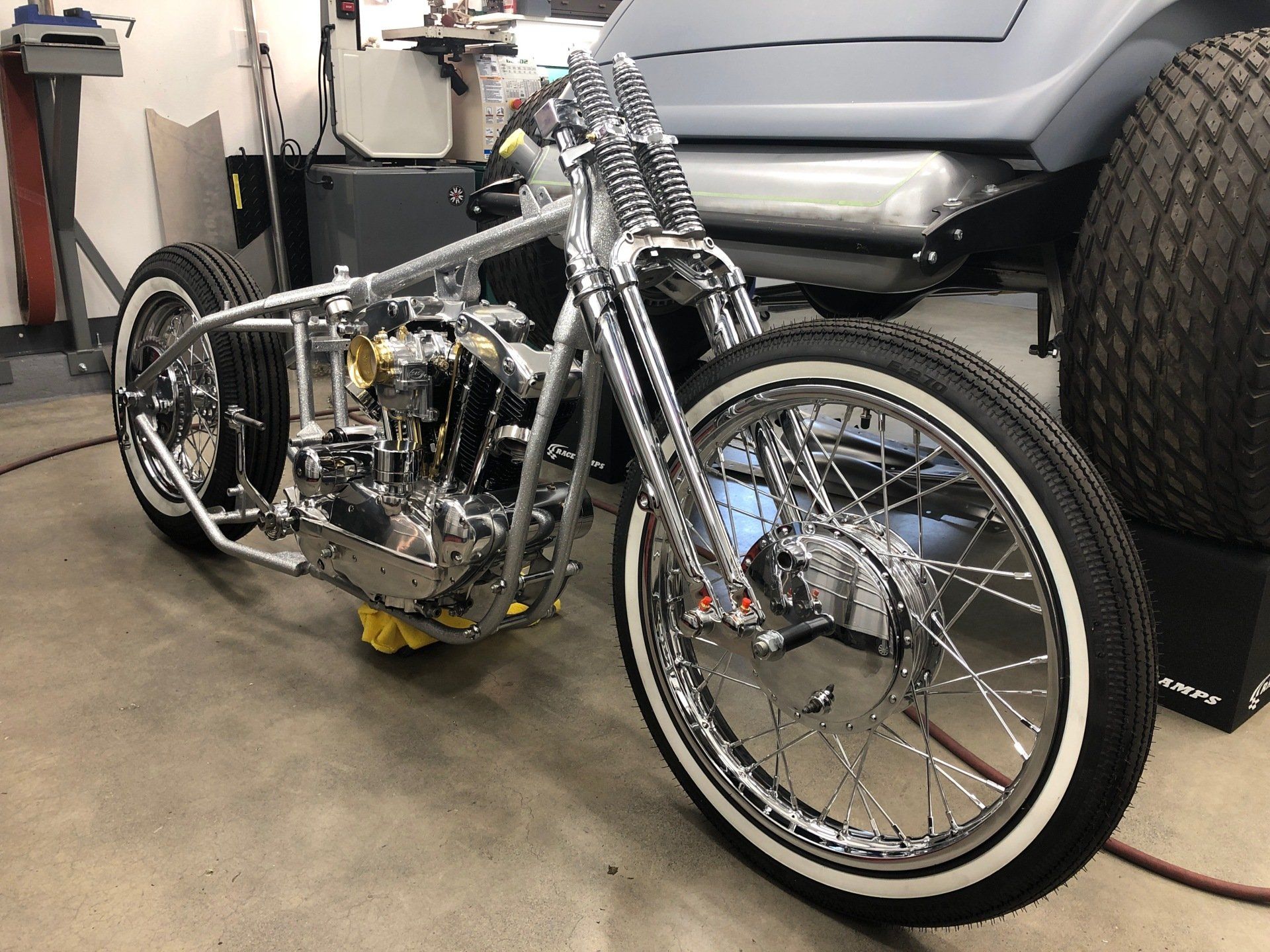 A motorcycle is sitting next to a golf cart in a garage.