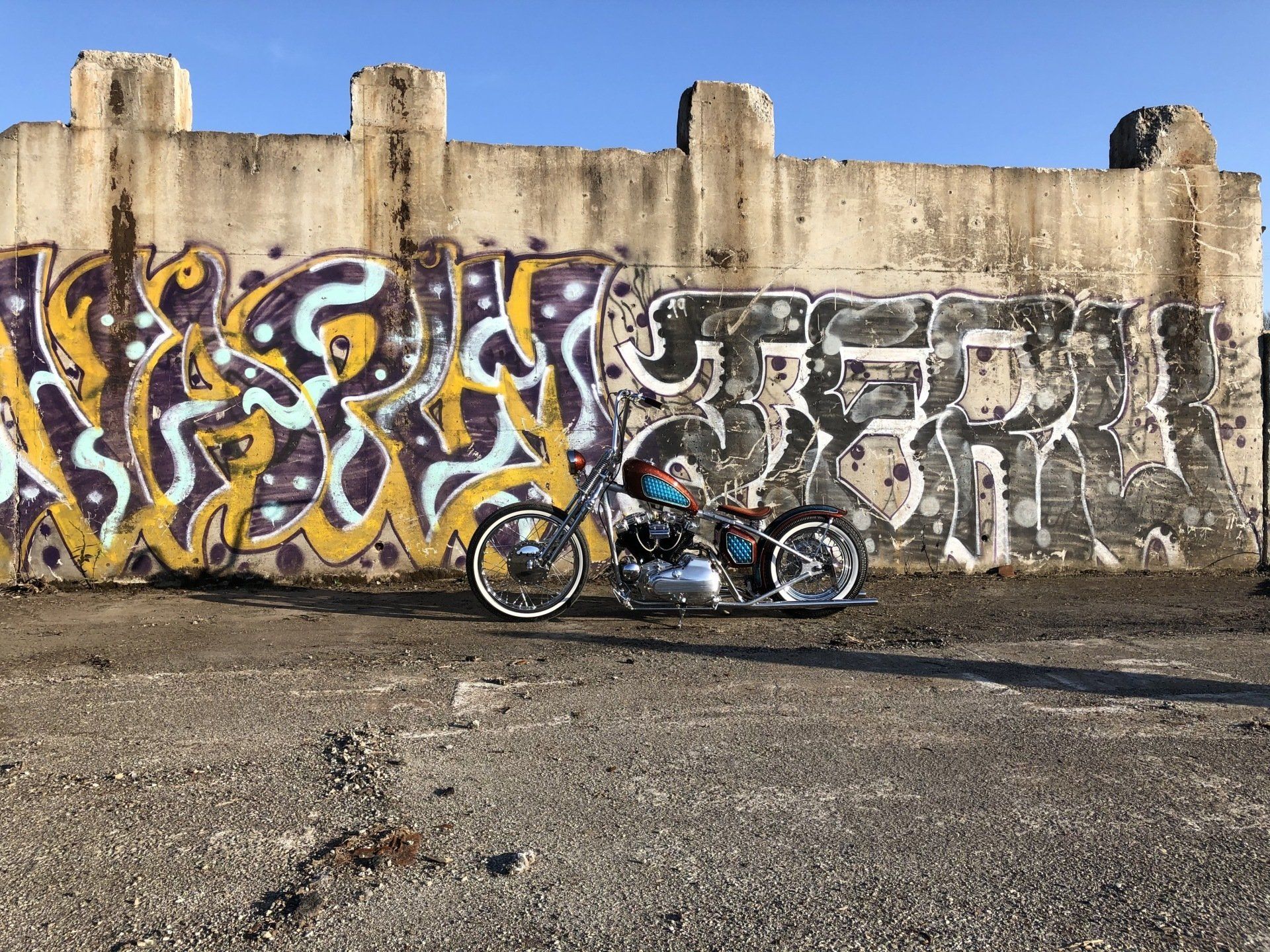 A motorcycle is parked in front of a wall with graffiti on it.