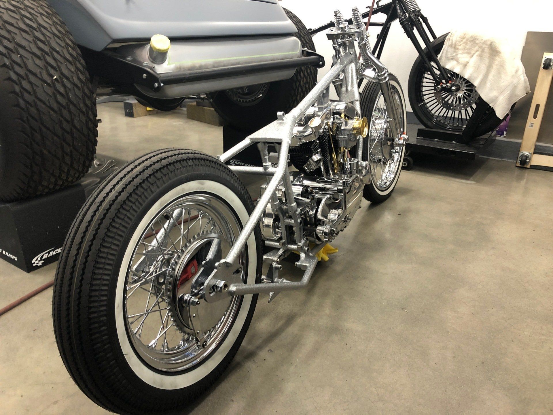 A motorcycle is parked in a garage next to a golf cart