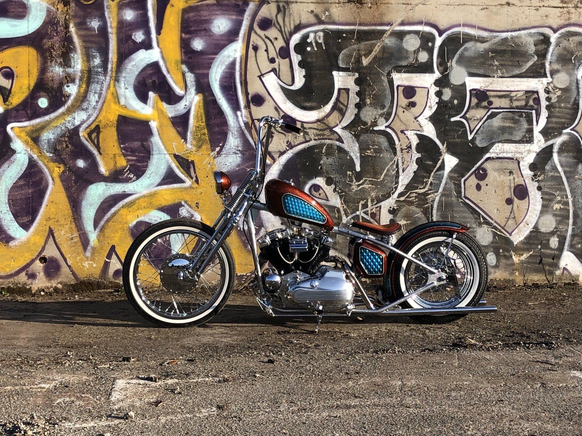 A motorcycle is parked in front of a graffiti covered wall.