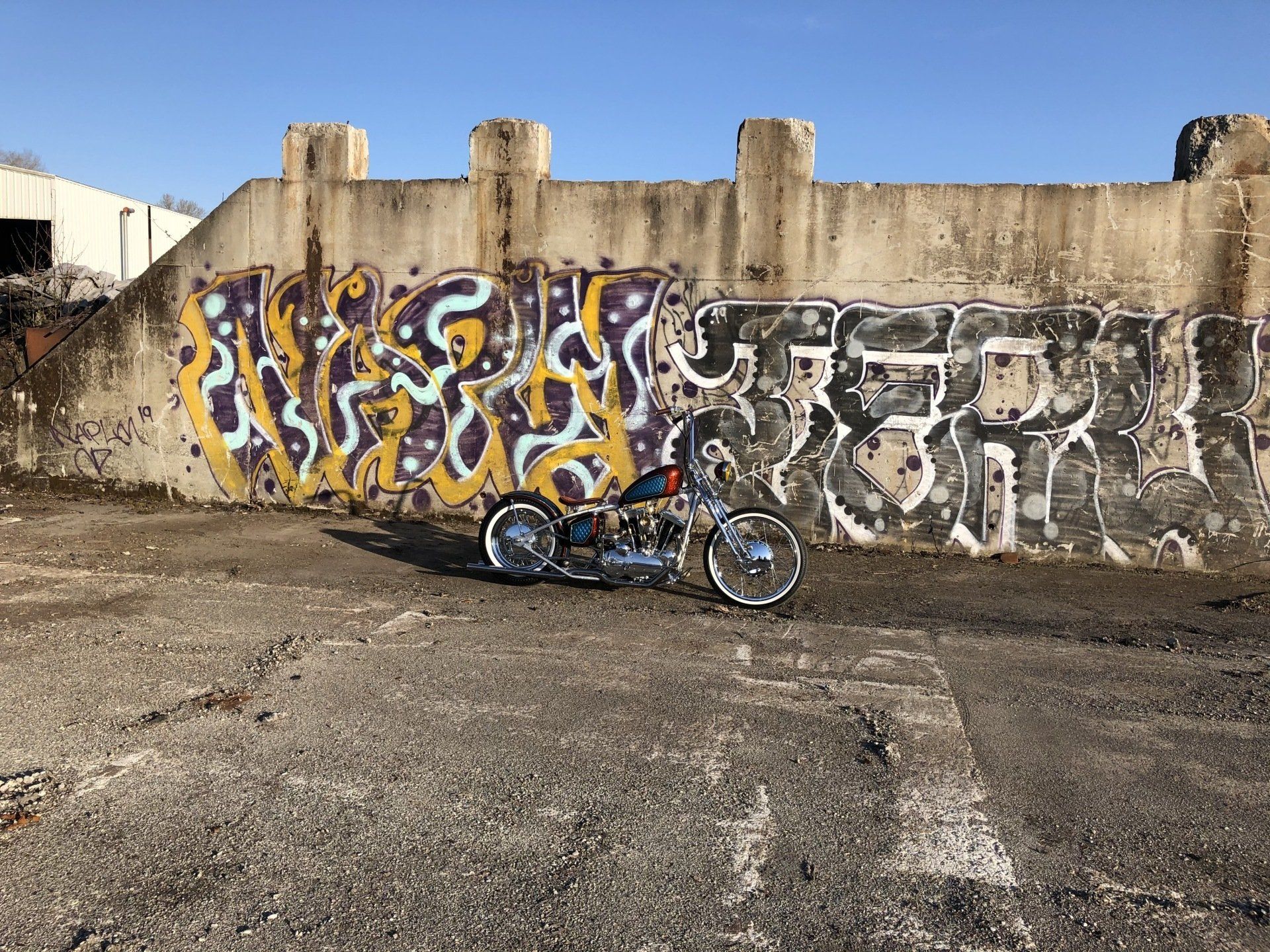 A motorcycle is parked in front of a wall with graffiti on it.