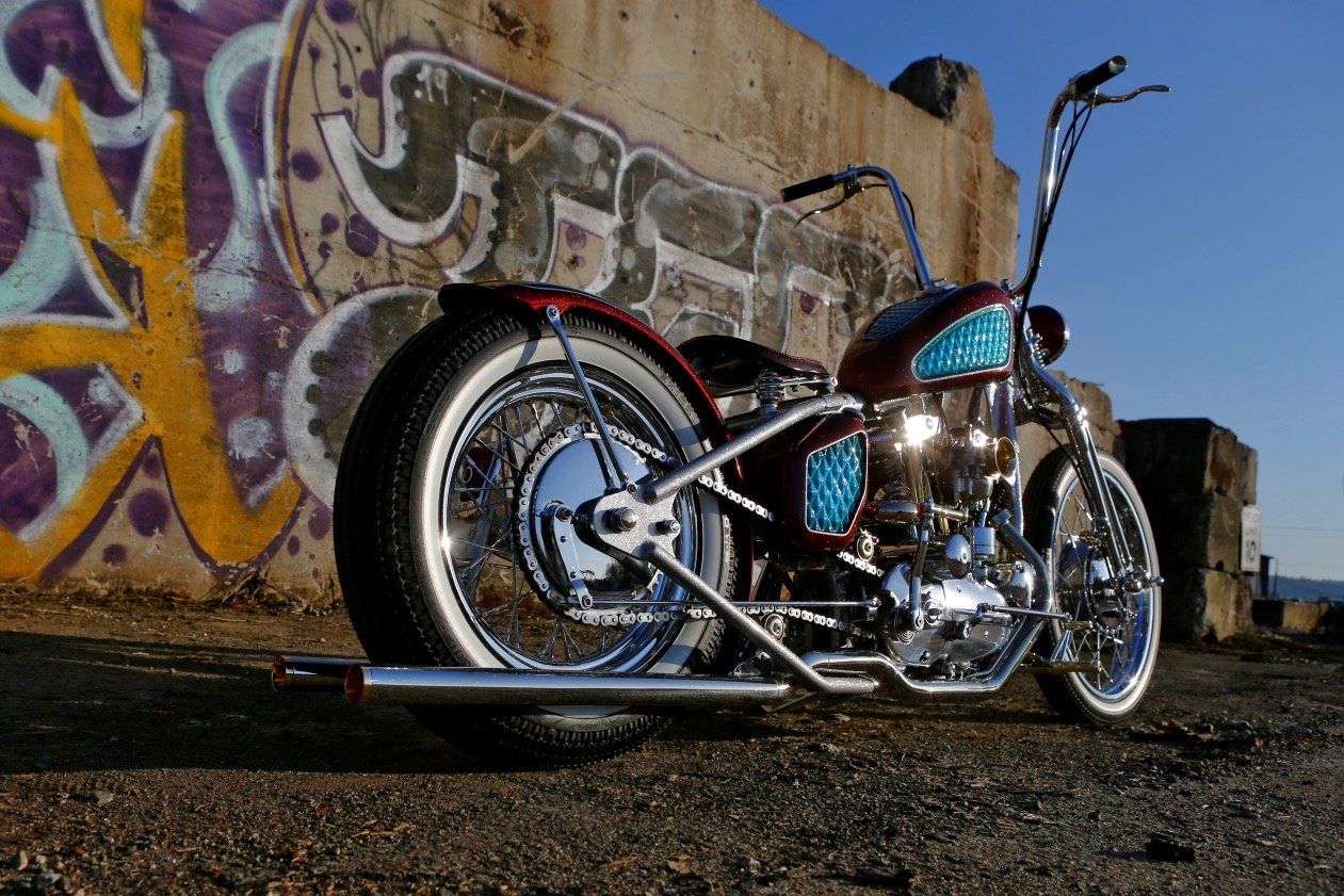 A motorcycle is parked in front of a wall with graffiti on it