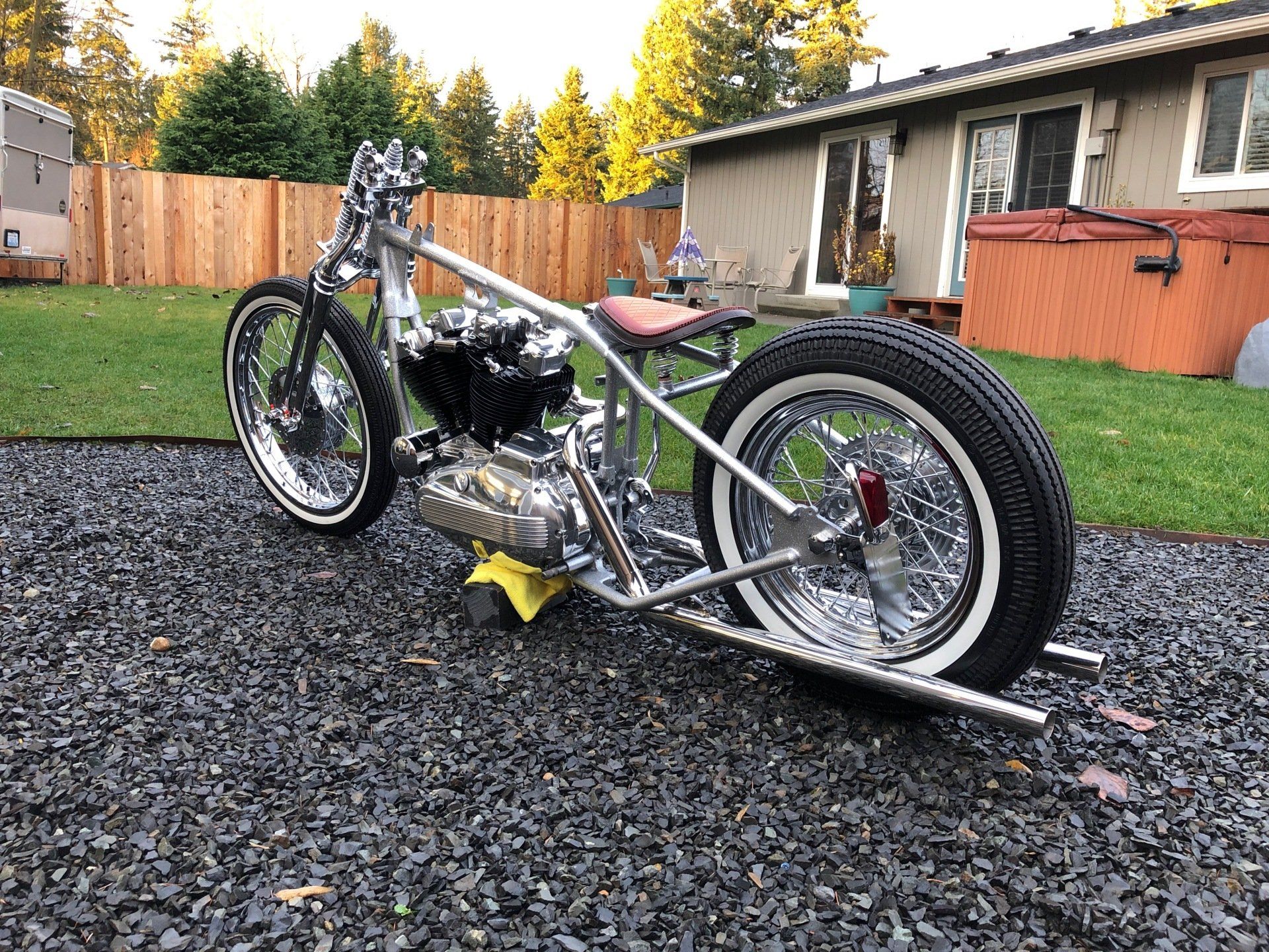A motorcycle is parked on gravel in front of a house.