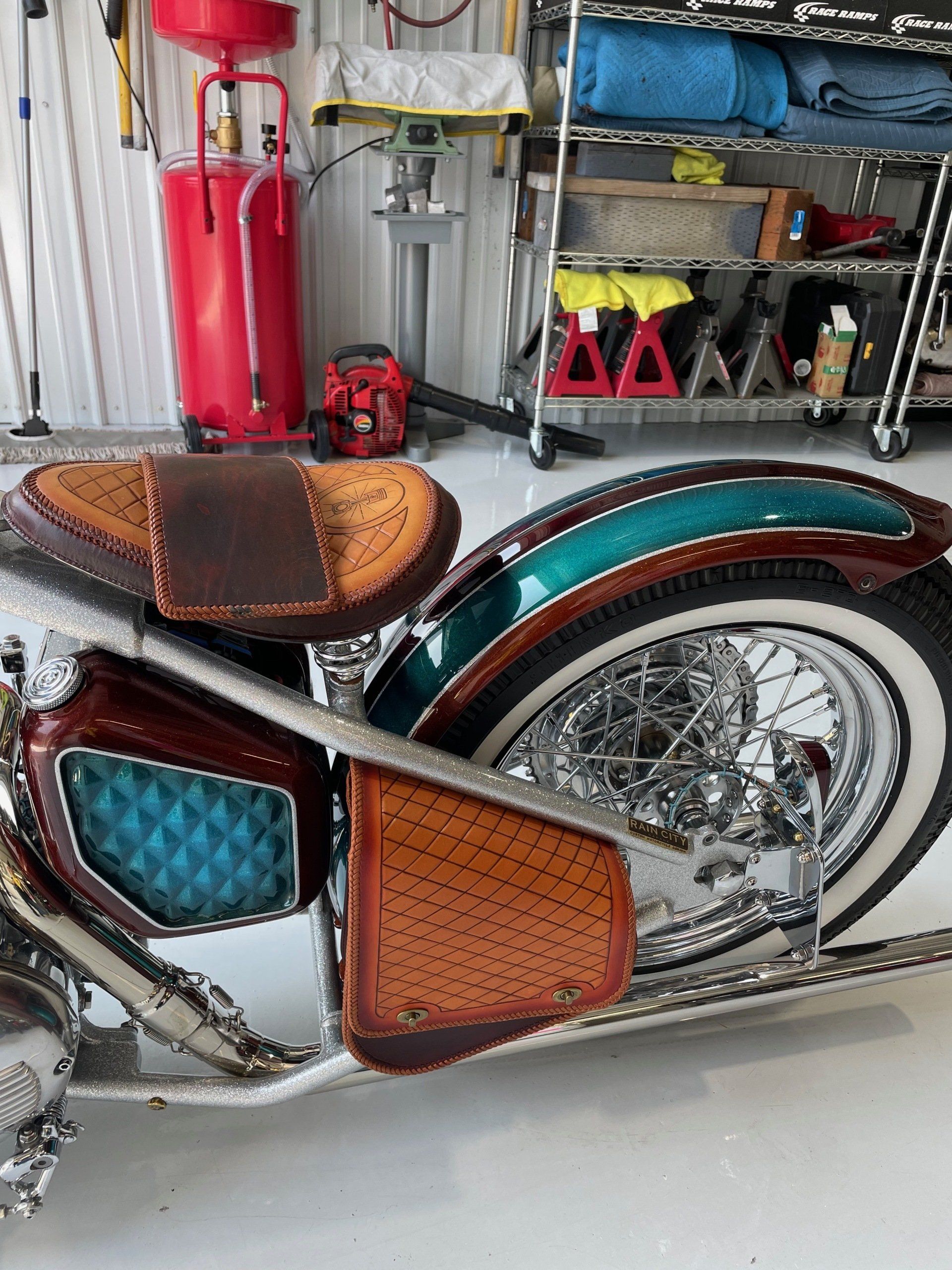 A motorcycle is parked in a garage with a vacuum cleaner in the background