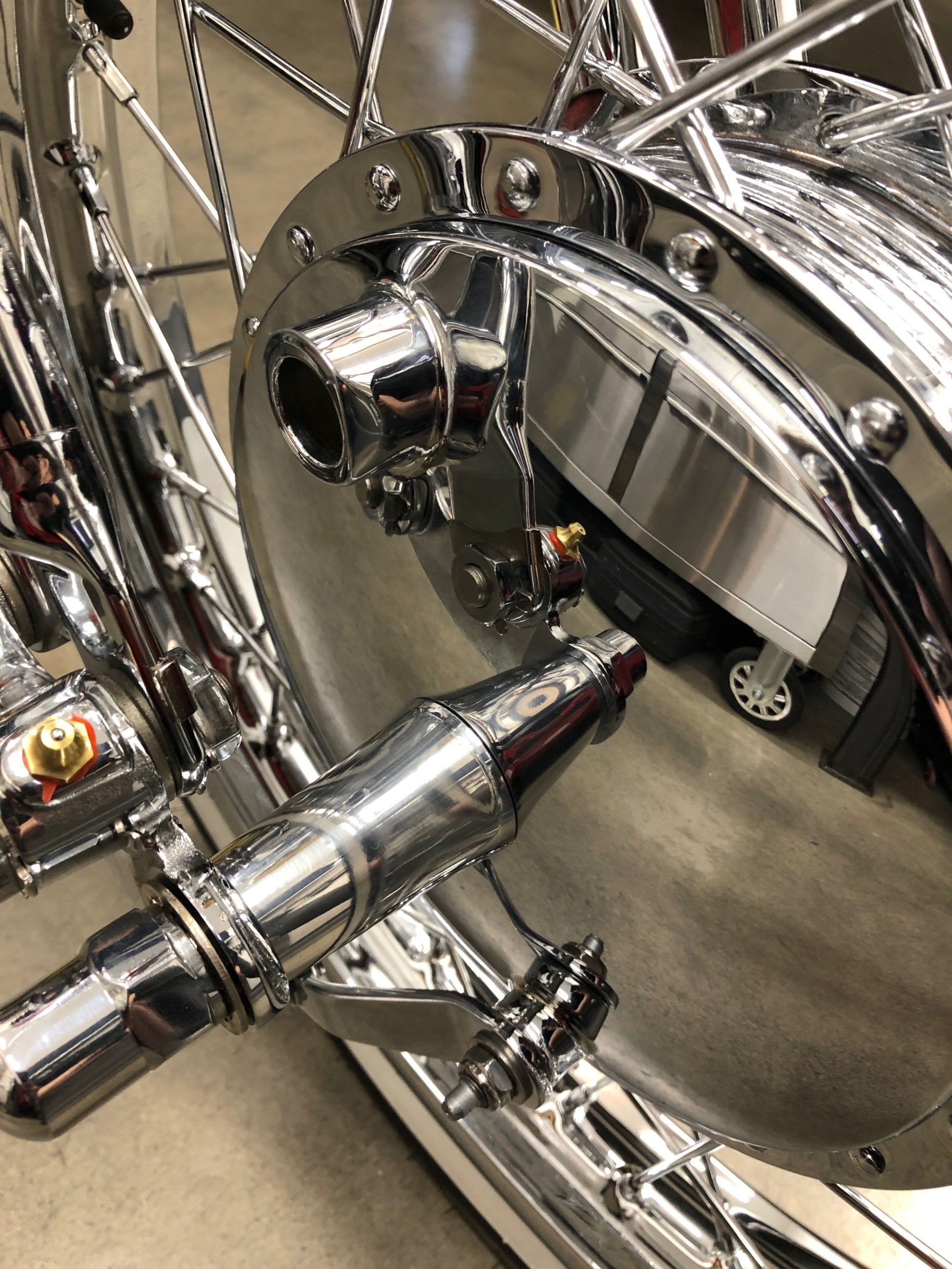 A close up of a chrome drum with a reflection of a car in it