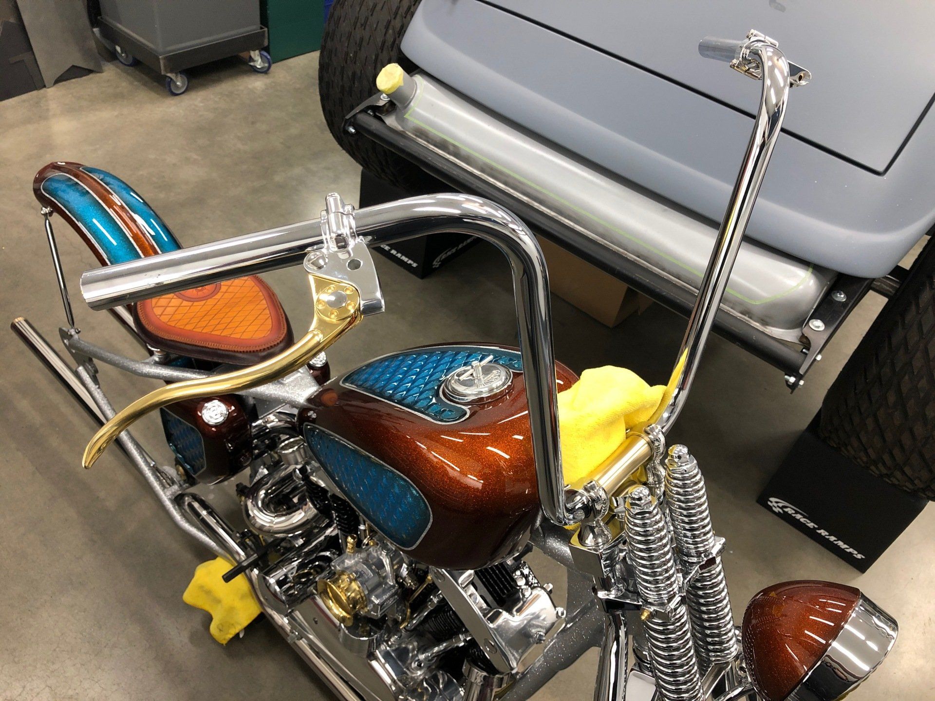 A motorcycle is parked next to a car in a garage.