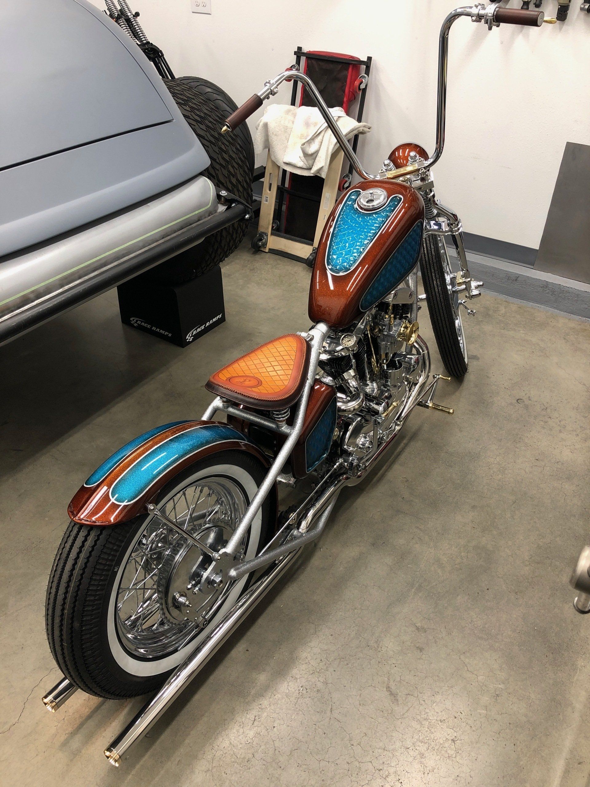 A motorcycle is parked in a garage next to a car.