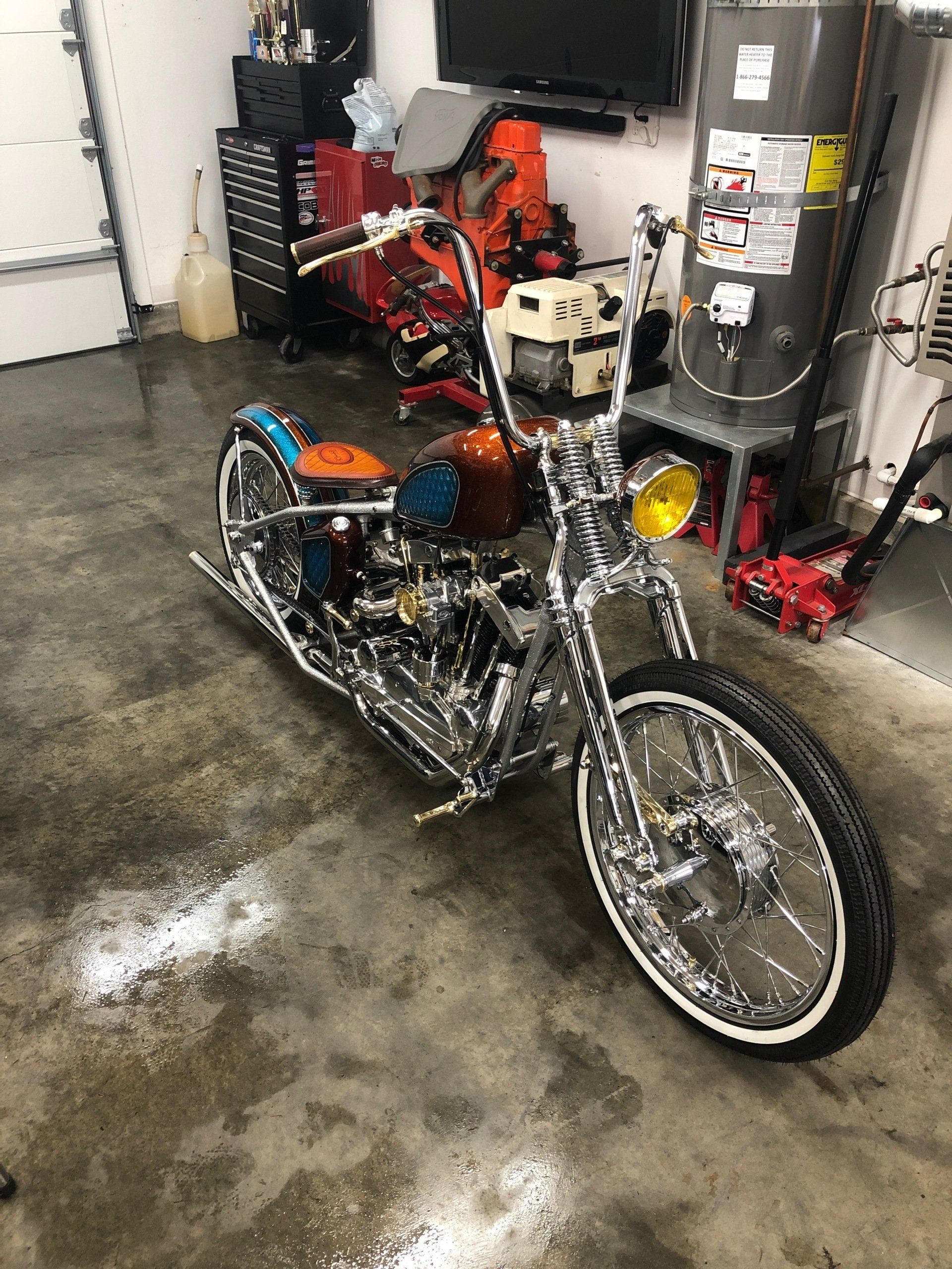 A motorcycle is parked in a garage next to a water heater.