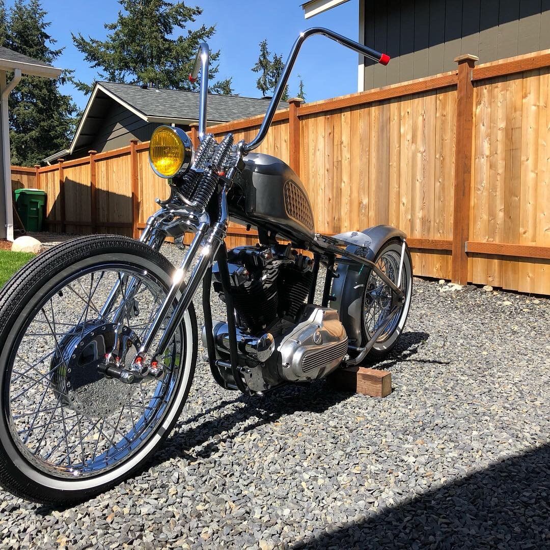 A motorcycle is parked in front of a wooden fence.