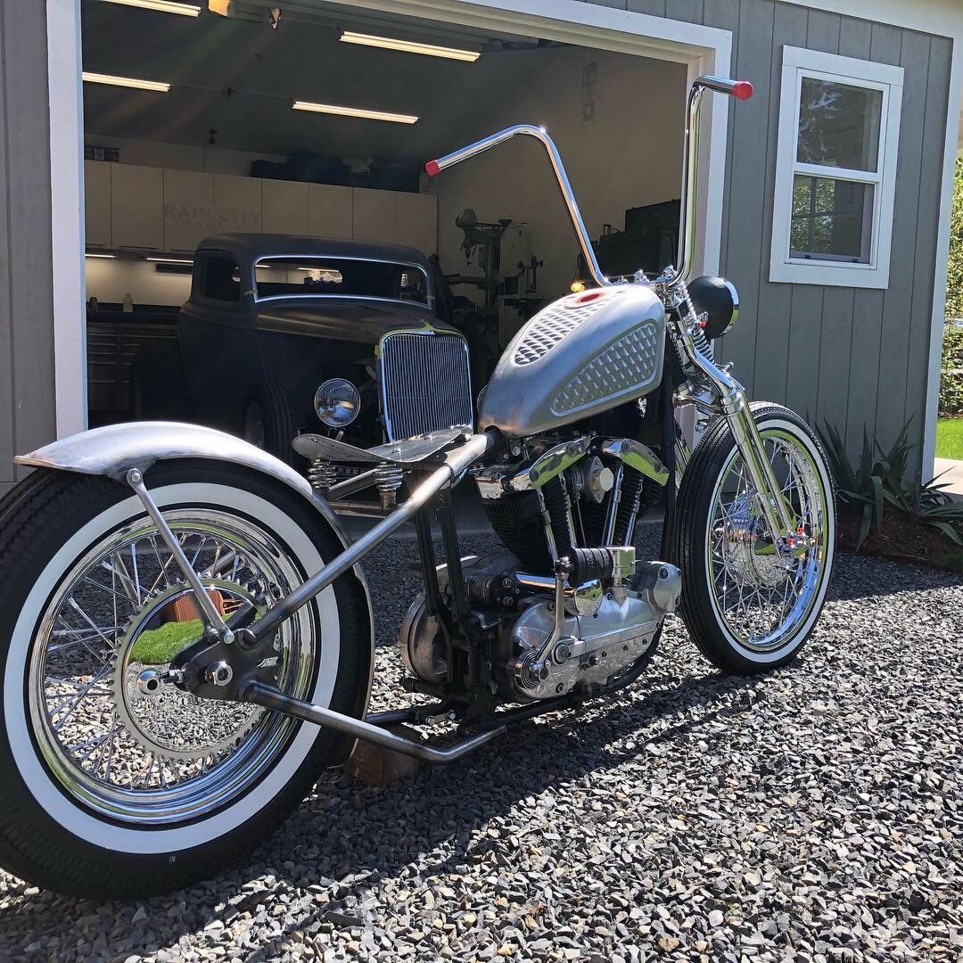 A motorcycle is parked in front of a garage next to a car.