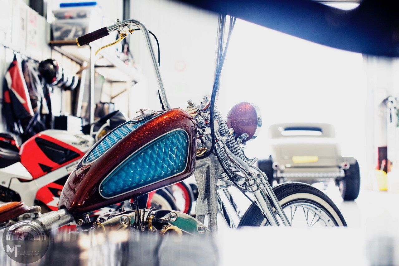 A motorcycle with a blue tank is parked in a garage.