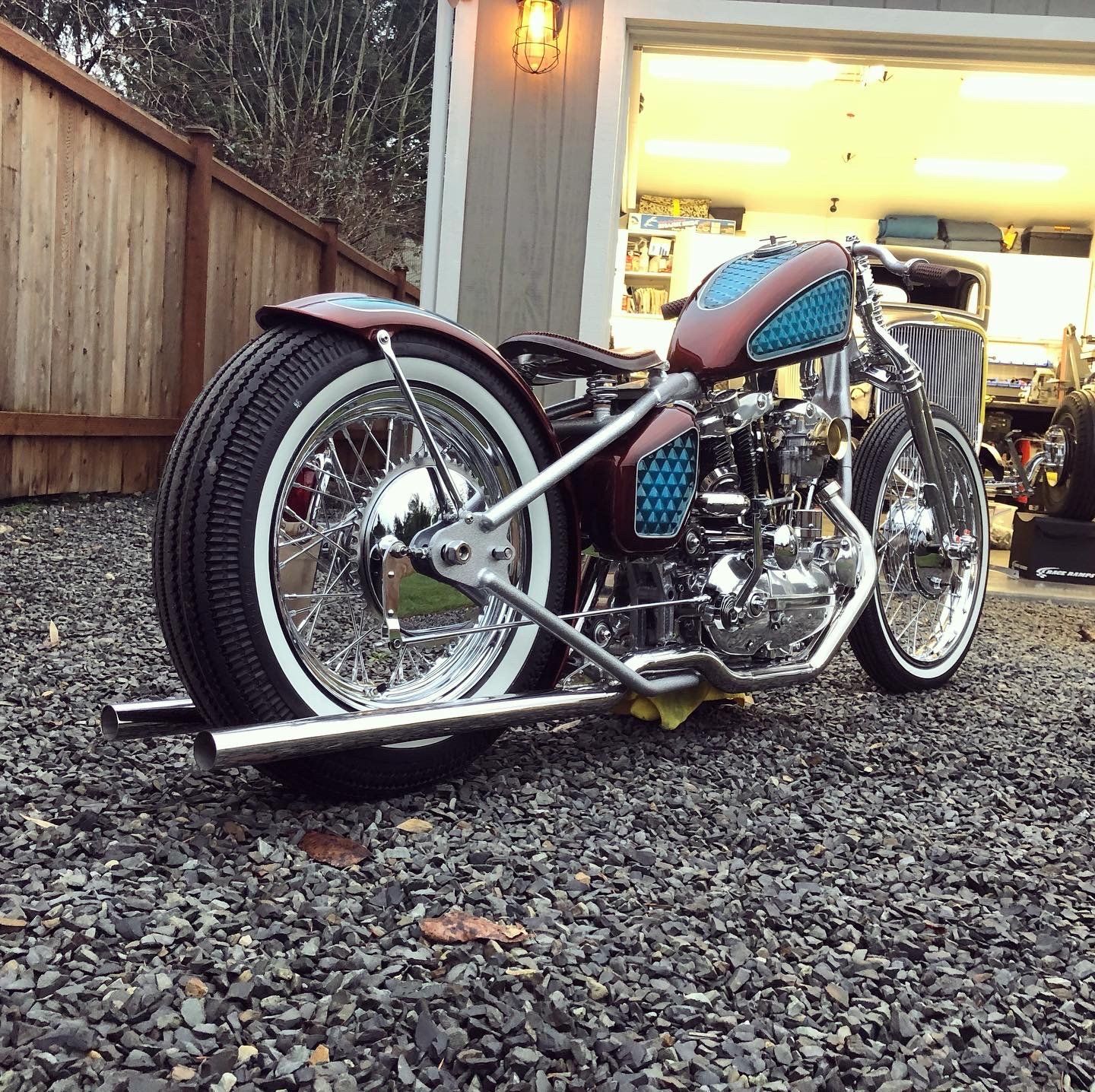 A motorcycle is parked in gravel in front of a garage