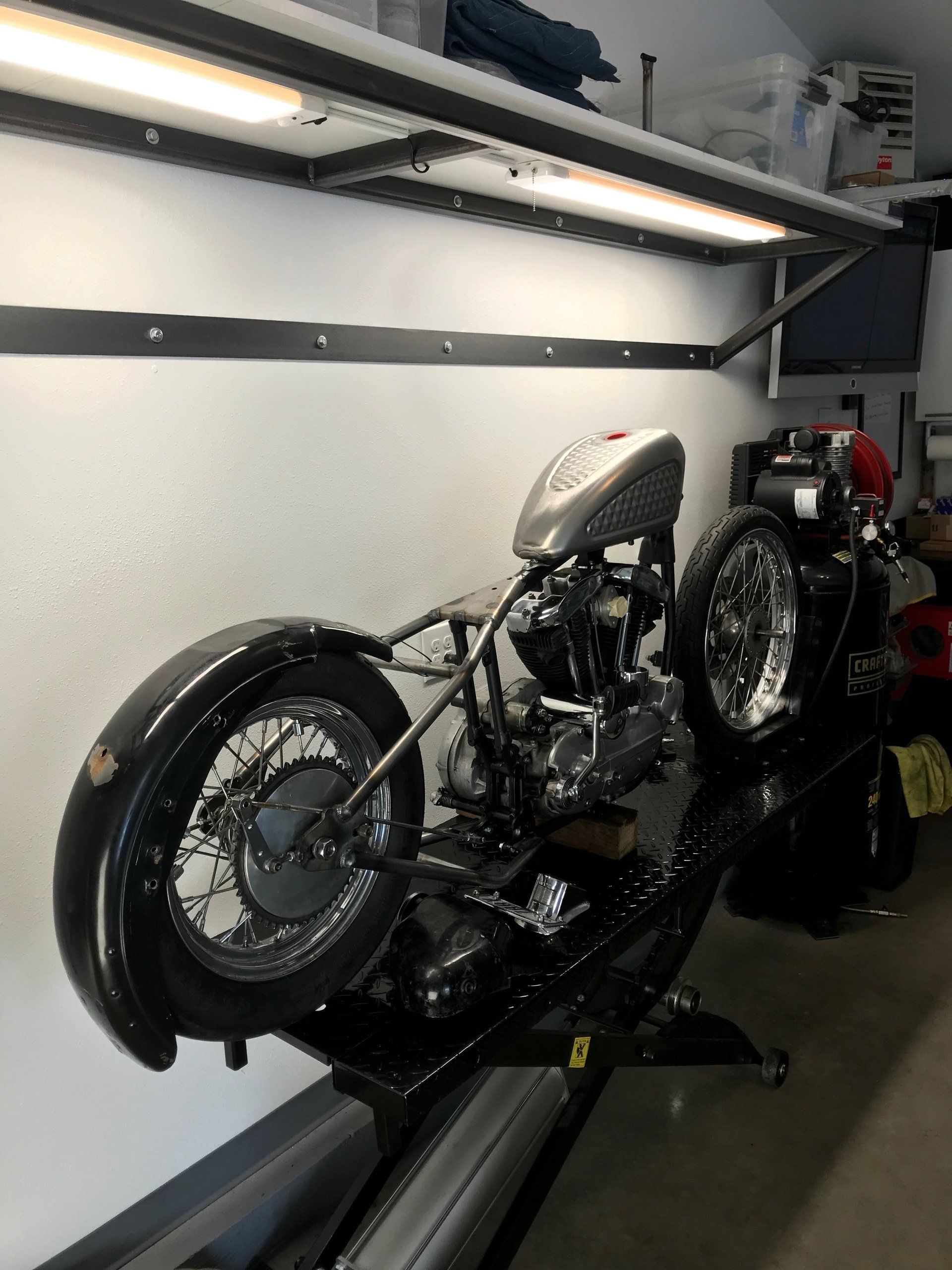 A motorcycle is sitting on a lift in a garage.